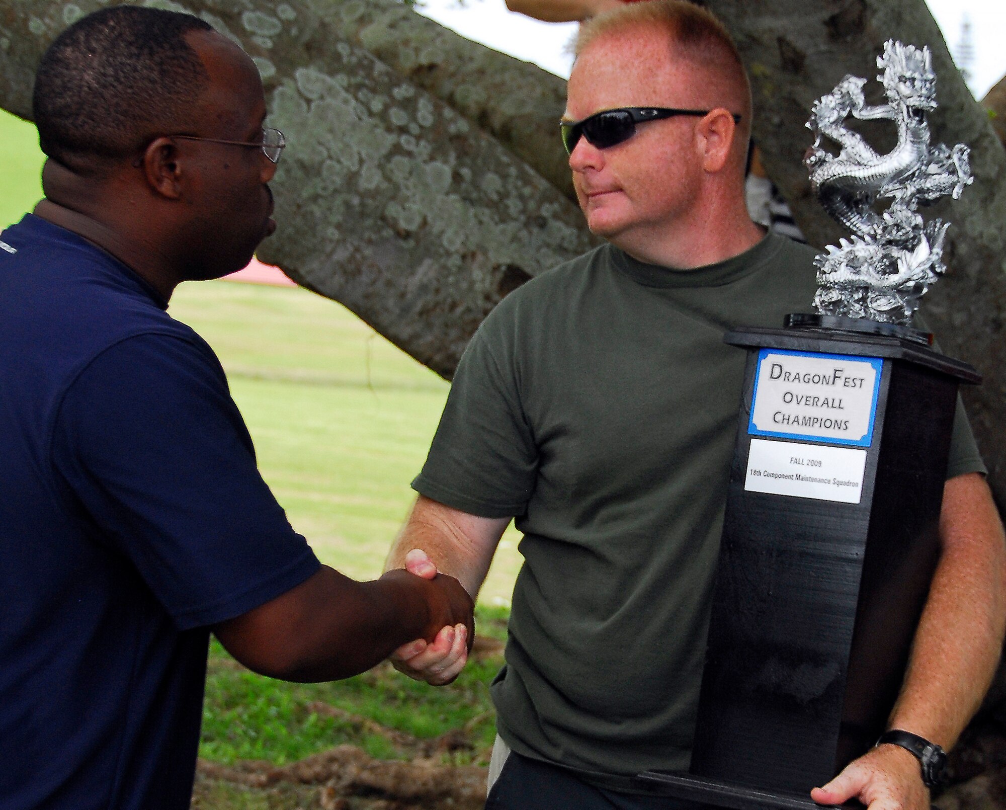 Tech. Sgt. Jermaine Boyd, 18th Component Maintenance Squadron and host of this year's DragonFest tournament, passes the trophy onto Marine Corps 1st Sgt. Beau Babkirk, 3rd Intelligence Battalion, after 3rd IB became Top Dragon Sept. 24. The tournament consisted of six events - ultimate football, volleyball, dodgeball, a chili cook-off, a 4-by-400 meter relay race and a tug-of-war competition. (U.S. Air Force photo/ Airman 1st Class Maeson L. Elleman)