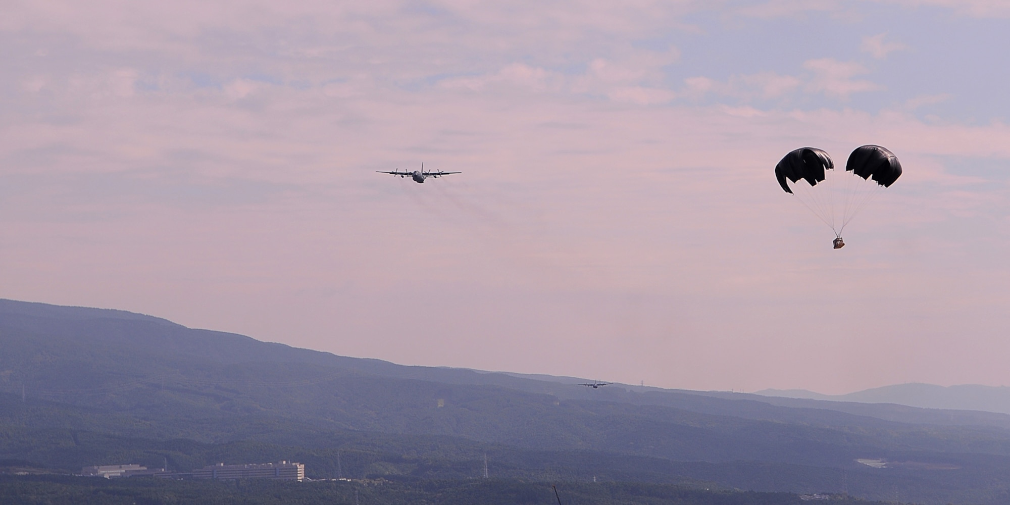YOKOTA AIR BASE, Japan -- A cross parachute carries a cargo load dropped out a C-130 Hercules, down to the Fuji Drop Zone during a practice run of the Low Cost, Low Altitude drop technique, here Oct. 7. (U.S. Air Force Photo/ Airman 1st Class Katrina R. Menchaca)