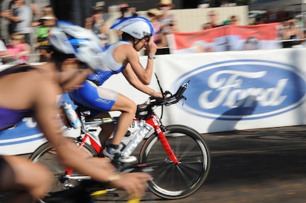 Capt. Jamie Turner adjusts her visor as she speeds by the crowd after transitioning from the 2.4-mile swim to the 112-mile bike race while competing in the 2010 Ironman World Championship Oct. 9, 2010, at Kona, Hawaii.  Captain Turner is a C-17 Globemaster III pilot at Joint Base Charleston, S.C. She finished with an overall time of 10:48:31.  (U.S. Air Force photo/Tech Sgt. Cohen A. Young)