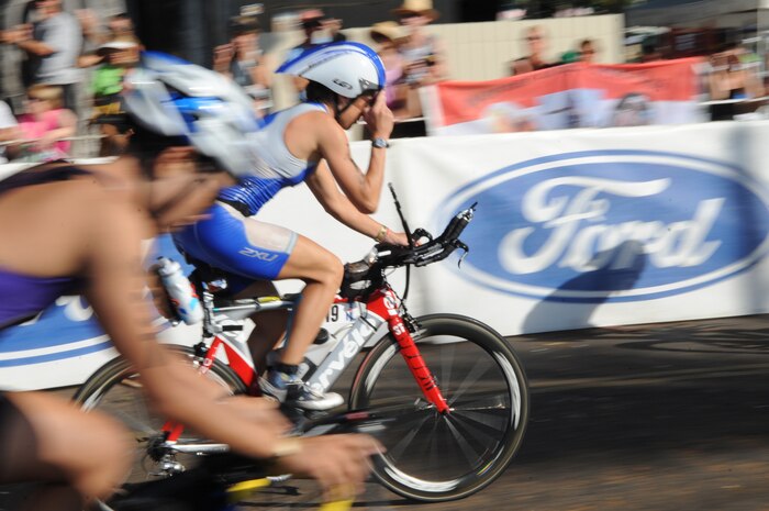Capt. Jamie Turner adjusts her visor as she speeds by the crowd after transitioning from the 2.4-mile swim to the 112-mile bike race while competing in the 2010 Ironman World Championship Oct. 9, 2010, at Kona, Hawaii.  Captain Turner is a C-17 Globemaster III pilot at Joint Base Charleston, S.C. She finished with an overall time of 10:48:31.  (U.S. Air Force photo/Tech Sgt. Cohen A. Young)