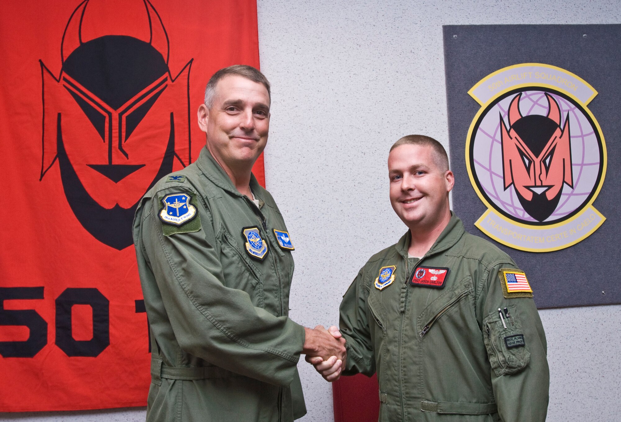 Col. Mike Minihan (left), 19th Airlift Wing commander, presents a coin Tuesday to Staff Sgt. Jason Carlton, a 50th Airlift Squadron C-130 flight engineer, for his selection as the Combat Airlifter of the Week. Sergeant Carlton safely returned aircraft during four in-flight emergencies and two ground emergencies during a recent deployment, saving 82 lives and $35 million in aircraft parts. (U.S. Air Force photo by Staff Sgt. Nestor Cruz)
