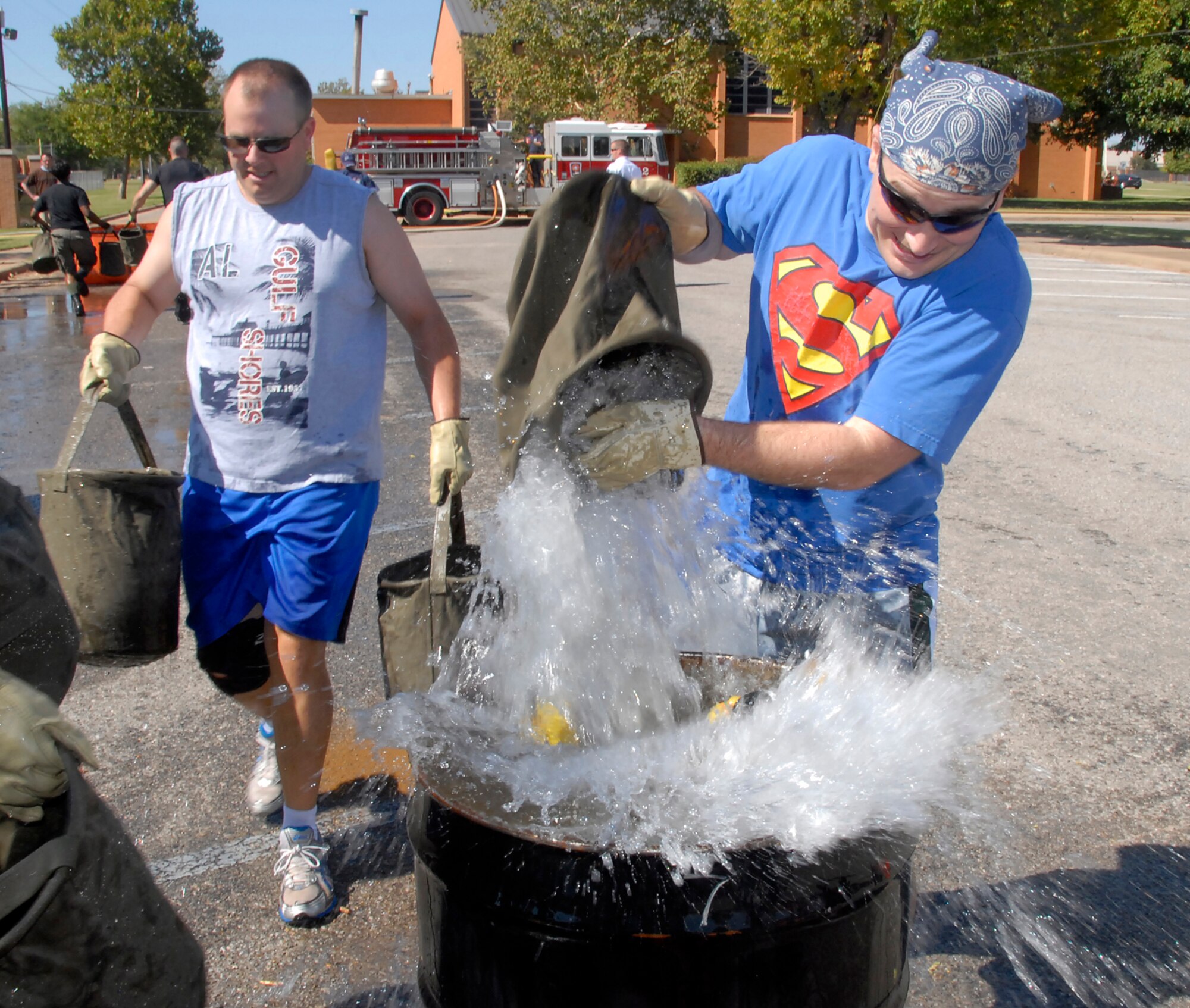Staff Sgt. Scotty Duncan, right, of the 82nd Training Wing Chapel Division team pours water into a 55-gallon drum Oct. 8 during the bucket brigade event of the inaugural Sheppard Fire Department Firefighter Olympics. Teams of five people competed in five events to determine who would be named champions. Also pictured is Tech. Sgt. David George, 82nd TRW Chapel Division. (U.S. Air Force photo/Mike Litteken)