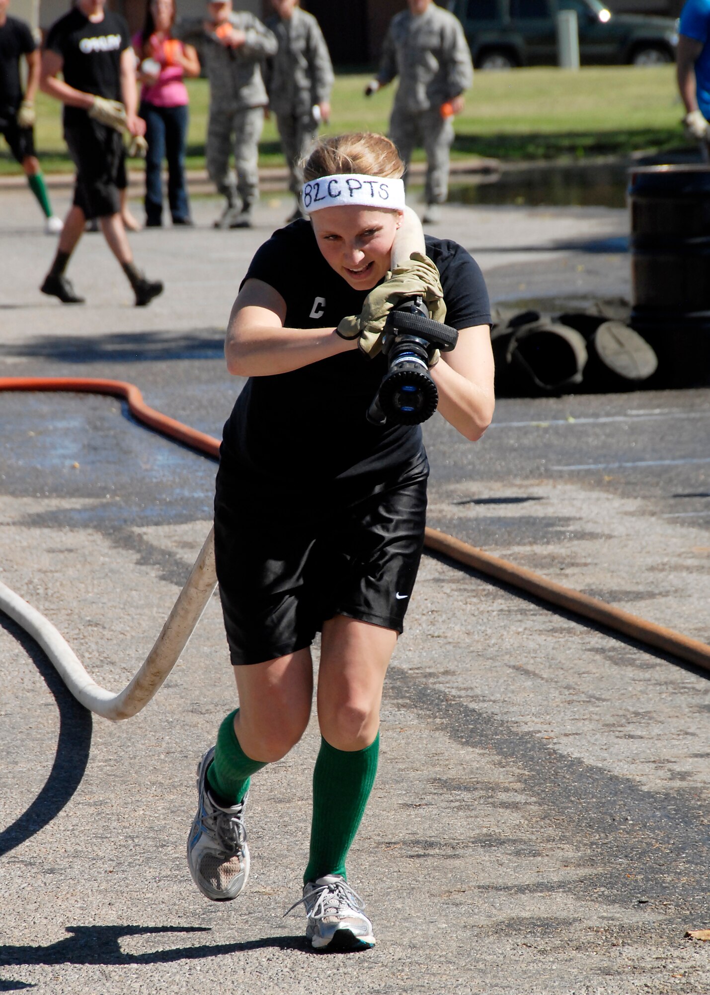 Capt. Kristen Schnell of the 82nd Comptroller Squadron tows a water-filled fire hose in one leg of the 200-foot charged hose line event Oct. 8 during the inaugural Sheppard Fire Department Firefighter Olympics. Eight teams of five people competed in five events for top honors. The 362nd Training Squadron was crowned champions by having the best cumulative time in all events. (U.S. Air Force photo/Mike Litteken)