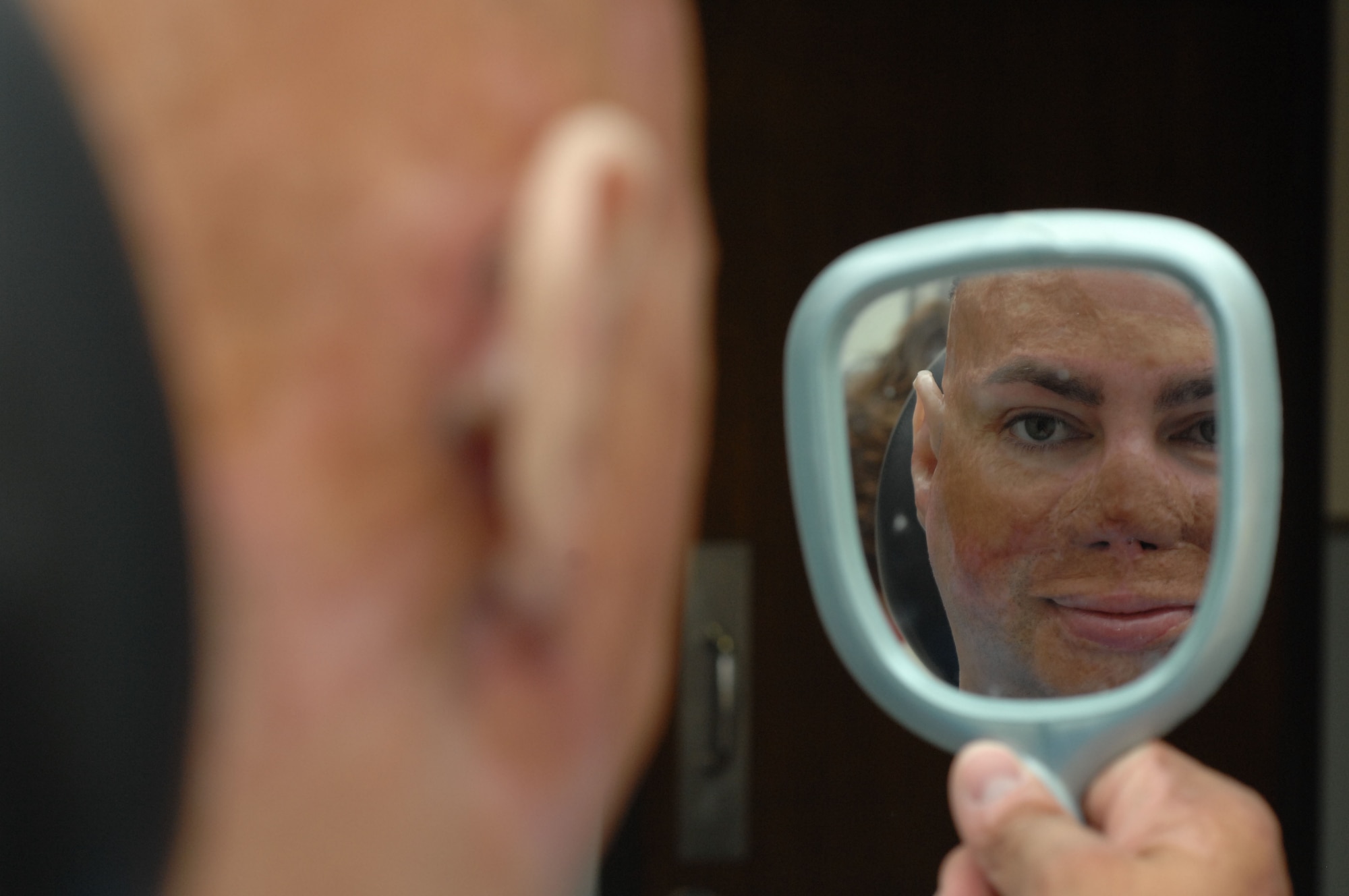 Retired Army Staff Sgt. Shilo Harris views the placement of his prosthetic ears Oct. 5, 2010, at Wilford Hall Medical Center, Lackland Air Force Base, Texas. Wounded in Iraq, Sergeant Harris has endured several medical procedures in the course of three years. During this time he has become a nationally recognized speaker, educating communities about support for wounded warriors. The 59th Medical Wing's Maxillofacial Prosthetics Department is one of only a few in the Department of Defense that creates prosthetic body parts, such as eyes, ears and noses. (U.S. Air Force photo/Staff Sgt. Robert Barnett)