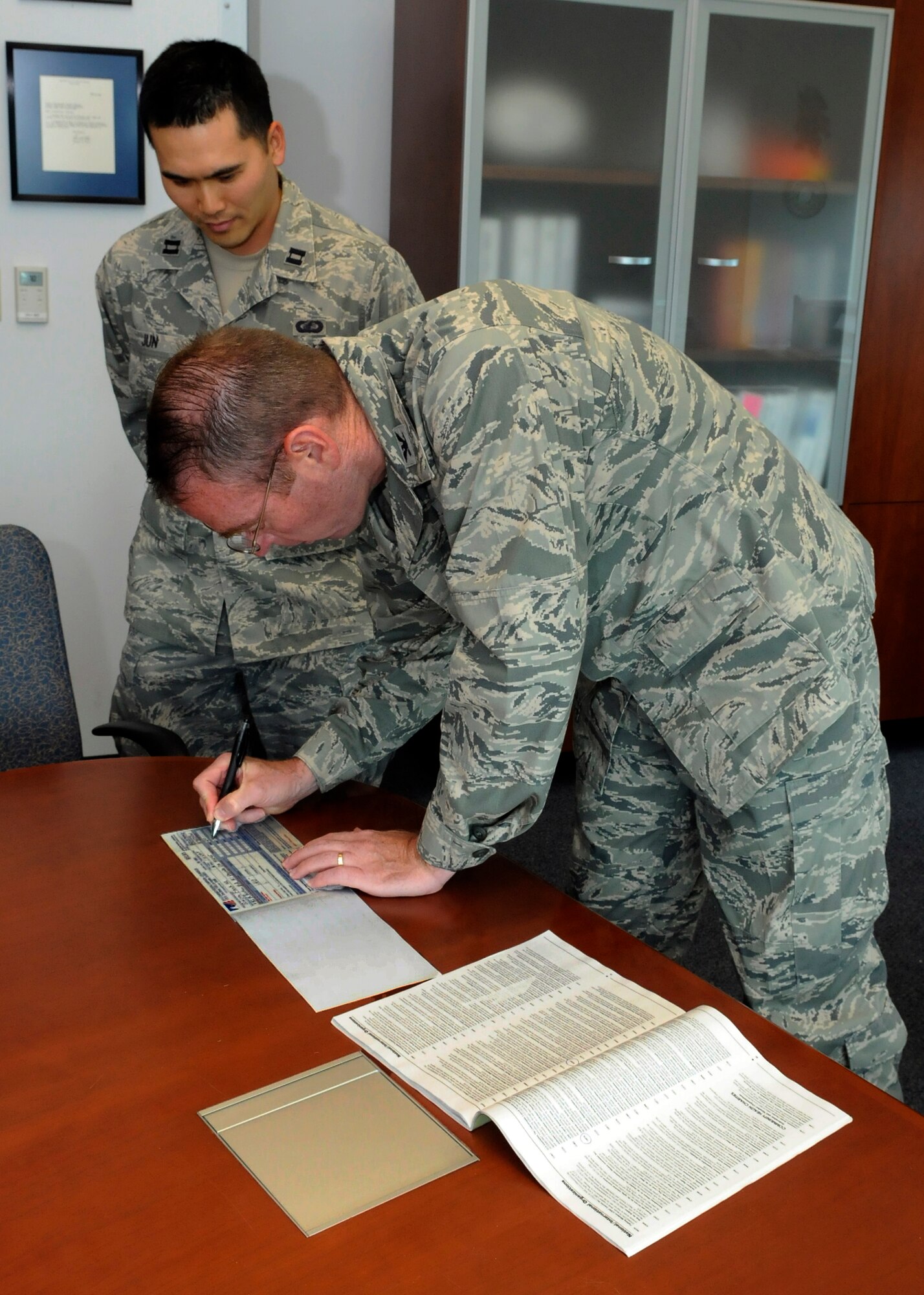 Col. Frank Simcox, 61st Air Base Group commander, signs his pledge form for this year's CFC campaign as Capt. Kyung Jun looks on. This year’s campaign runs from Oct 13 until Oct. 29. (Photo by Jim Gordon)