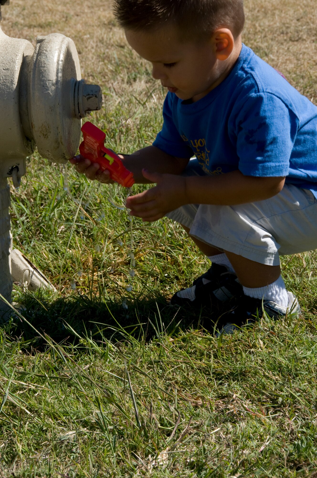 GOODFELLOW AIR FORCE BASE, Texas – Gunnar Truskett, 2, fills up his water gun at a hydrant, while his father, 17th Contracting Squadron commander, Maj. Garrett Truskett competes in the 6th annual Firefighter Muster at the fire station Oct. 8. The muster was part of the Fire Prevention Awareness Week, to spread the word on fire and smoke alarm safety. (U.S. Air Force photo/ Senior Airman Tong Duong)