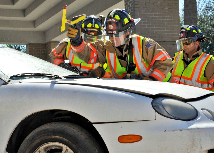 Daniel Bye, 96th Civil Engineer Squadron firefighter, uses a hammer to break the windshield out during the car extraction demonstration at Eglin’s base exchange Oct.  8.  The firefighters demonstrated how quickly they can open up a car to free a trapped victim of an accident.  The demonstration closed out fire prevention week at Eglin.  (U.S. Air Force photo/Samuel King Jr.)