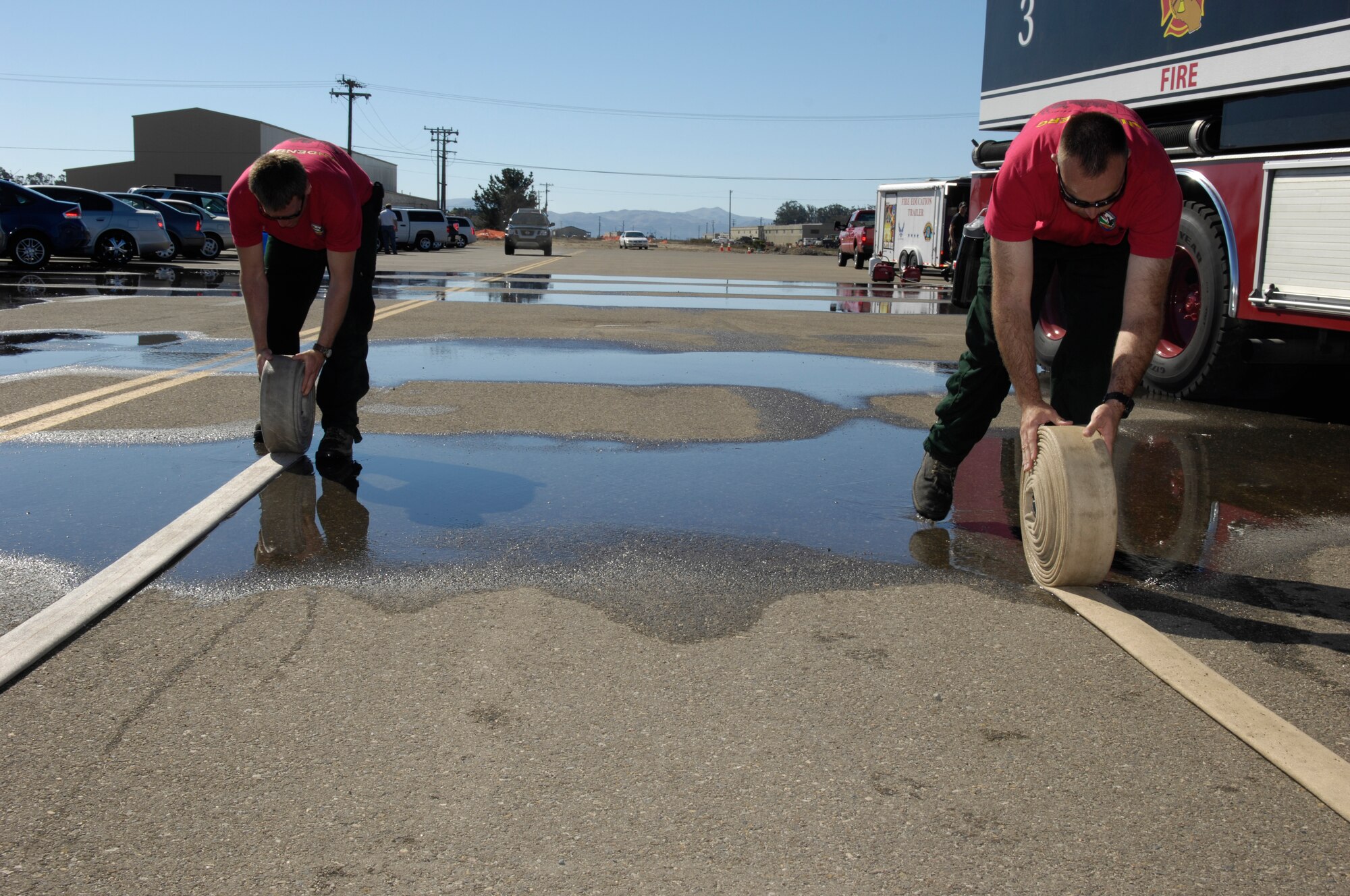 VANDENBERG AIR FORCE BASE, Calif. – Patrick Kennedy and Trent Ogan, both 30th Civil Engineer Squadron firefighters, roll up hoses during this year’s Fire Muster held at the base parade grounds Friday, Oct. 8, 2010. The Fire Muster is a friendly competition between squadrons that demonstrates what a firefighter faces both physically and mentally. (U.S. Air Force photo/Airman 1st Class Lael Huss) 