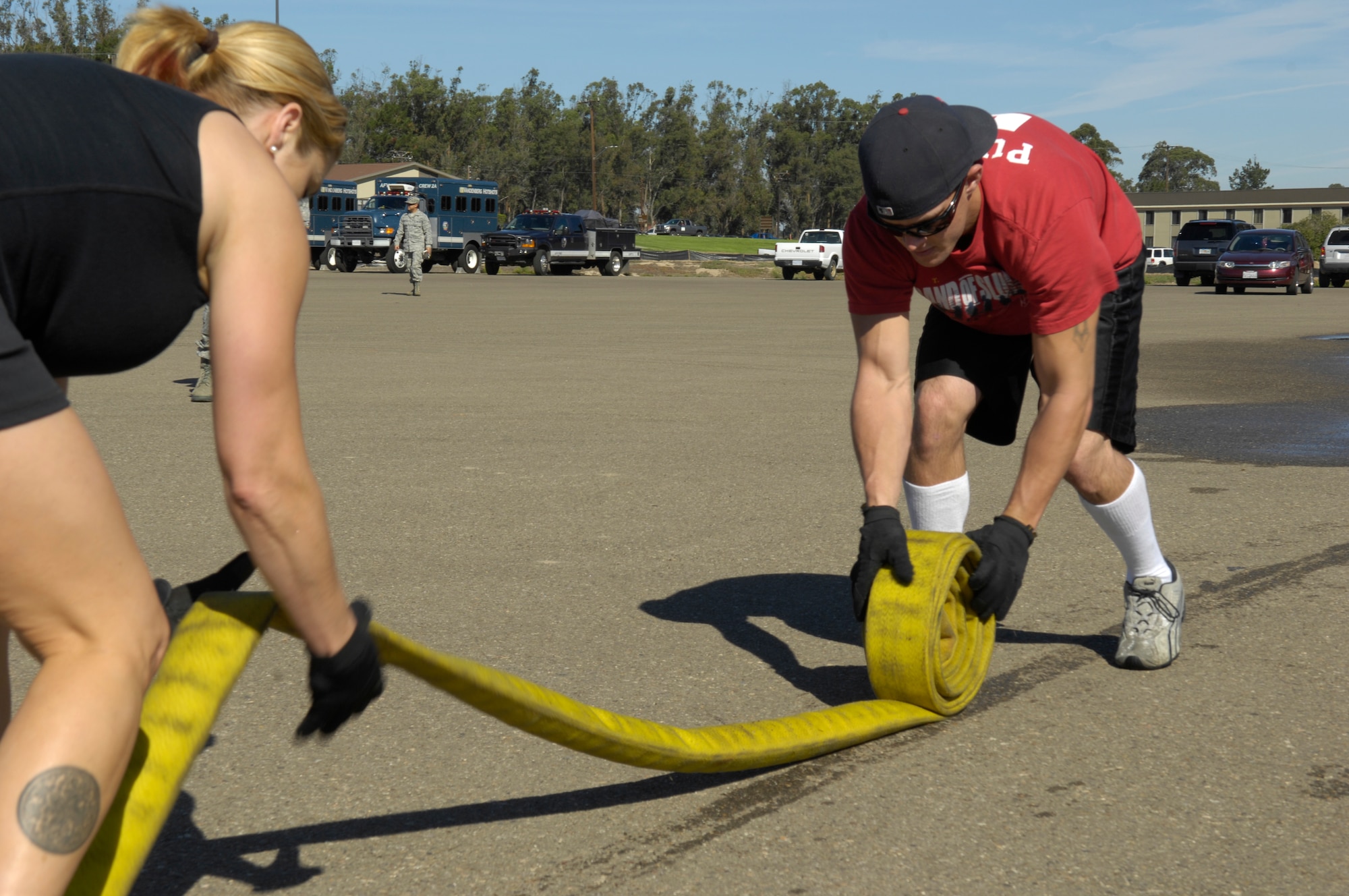 VANDENBERG AIR FORCE BASE, Calif. – Senior Airman Ryan Marshall and Tech. Sgt. Tracey Drake, both from the 30th Medical Group, quickly roll a fire hose during an obstacle course at the Fire Muster here Friday, Oct. 8, 2010. The Fire Muster is a friendly competition between squadrons held at the parade grounds. (U.S. Air Force photo/Airman 1st Class Lael Huss)