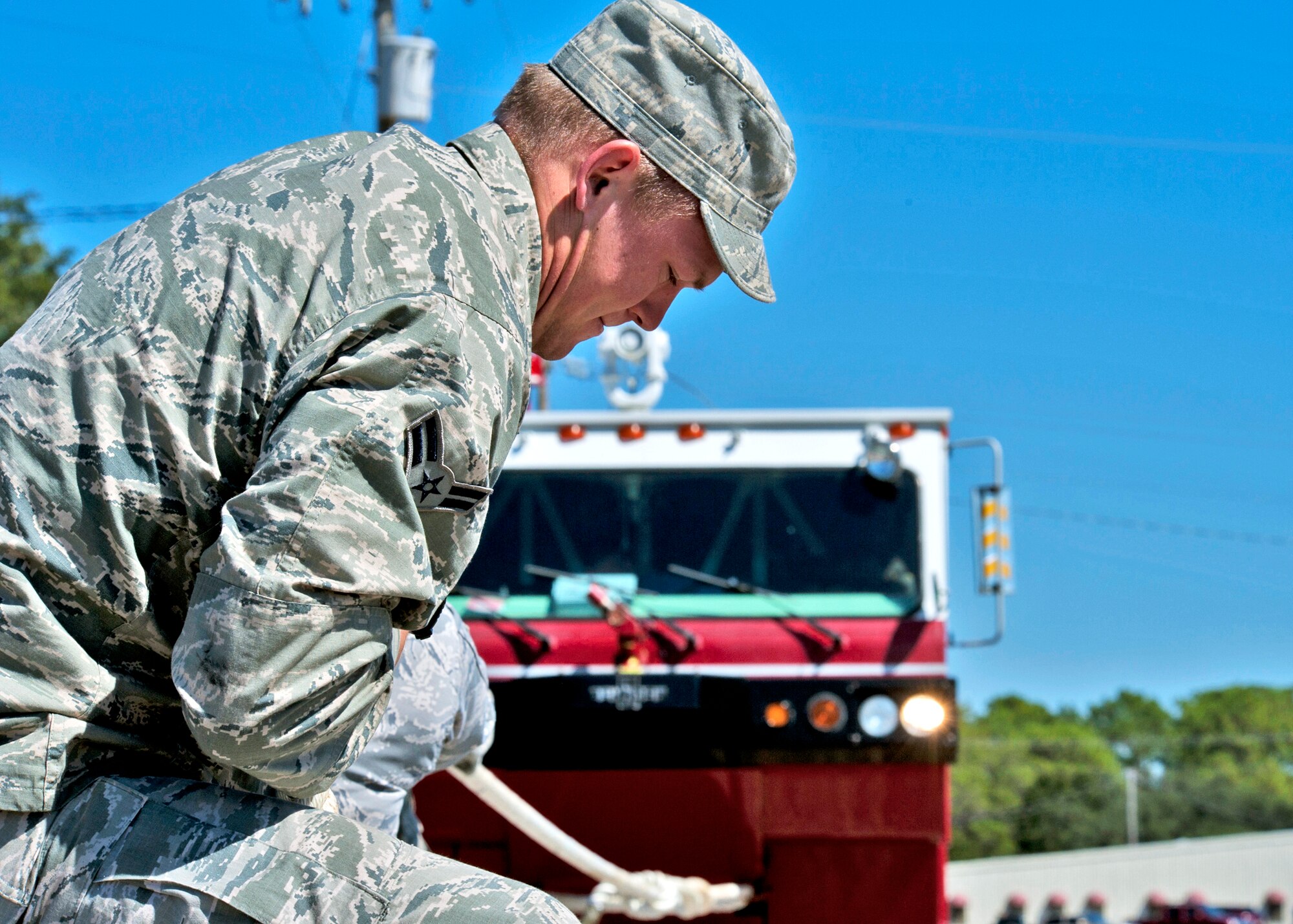 An Airman from the base fire department demonstrates the fire engine pull during the Fire Muster Challenge Oct. 4 at Eglin Air Force Base, Fla.  Teams competed in the challenge that included a ladder and hose carry, fire engine pull, and water relay.  (U.S. Air Force photo/Samuel King Jr.)