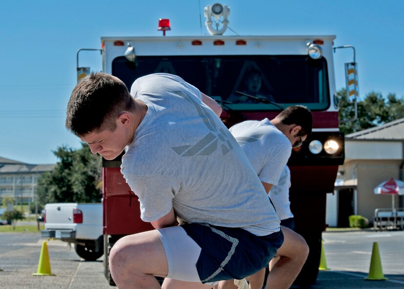 Senior Airman Nickolas Cox, 96th Civil Engineer Squadron, leads his team in pulling a base fire truck during the Fire Muster Challenge Oct. 4 at Eglin Air Force Base, Fla.  Teams competed in the challenge that included a ladder and hose carry, fire engine pull, and water relay.  (U.S. Air Force photo/Samuel King Jr.)