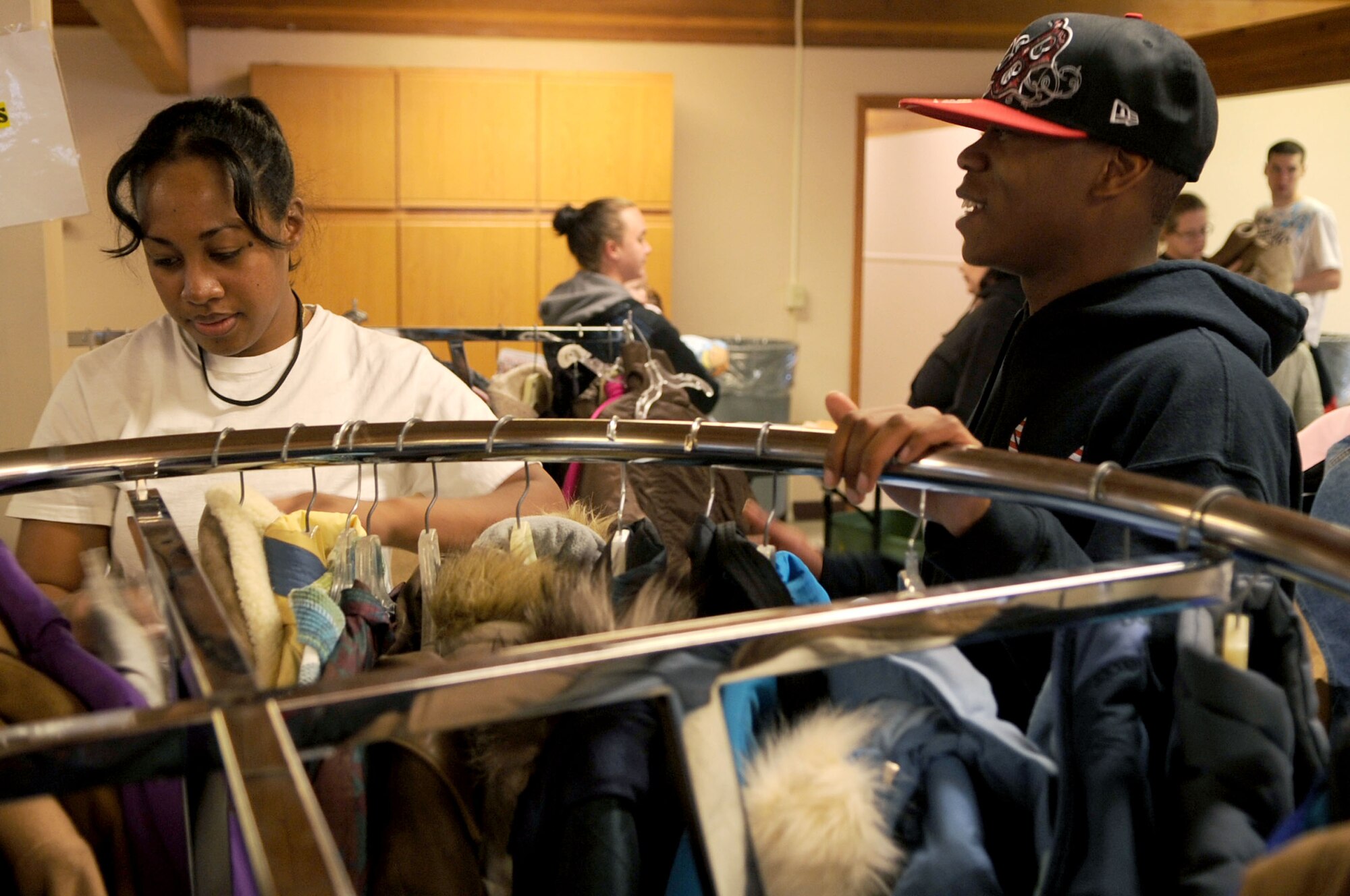 Airmen 1st Class Renee Misaalefua and Darryl McCoo, 319th Logistics Readiness Squadron, browse help a member of the local community find a coat at the Salvation Army winter clothing distribution Oct. 6 in Grand Forks, N.D. Volunteers from Grand Forks Air Force Base helped the Salvation Army with set-up, tear-down and handing out winter clothing items.  (U.S. Air Force photo by Senior Airman Amanda N. Stencil)