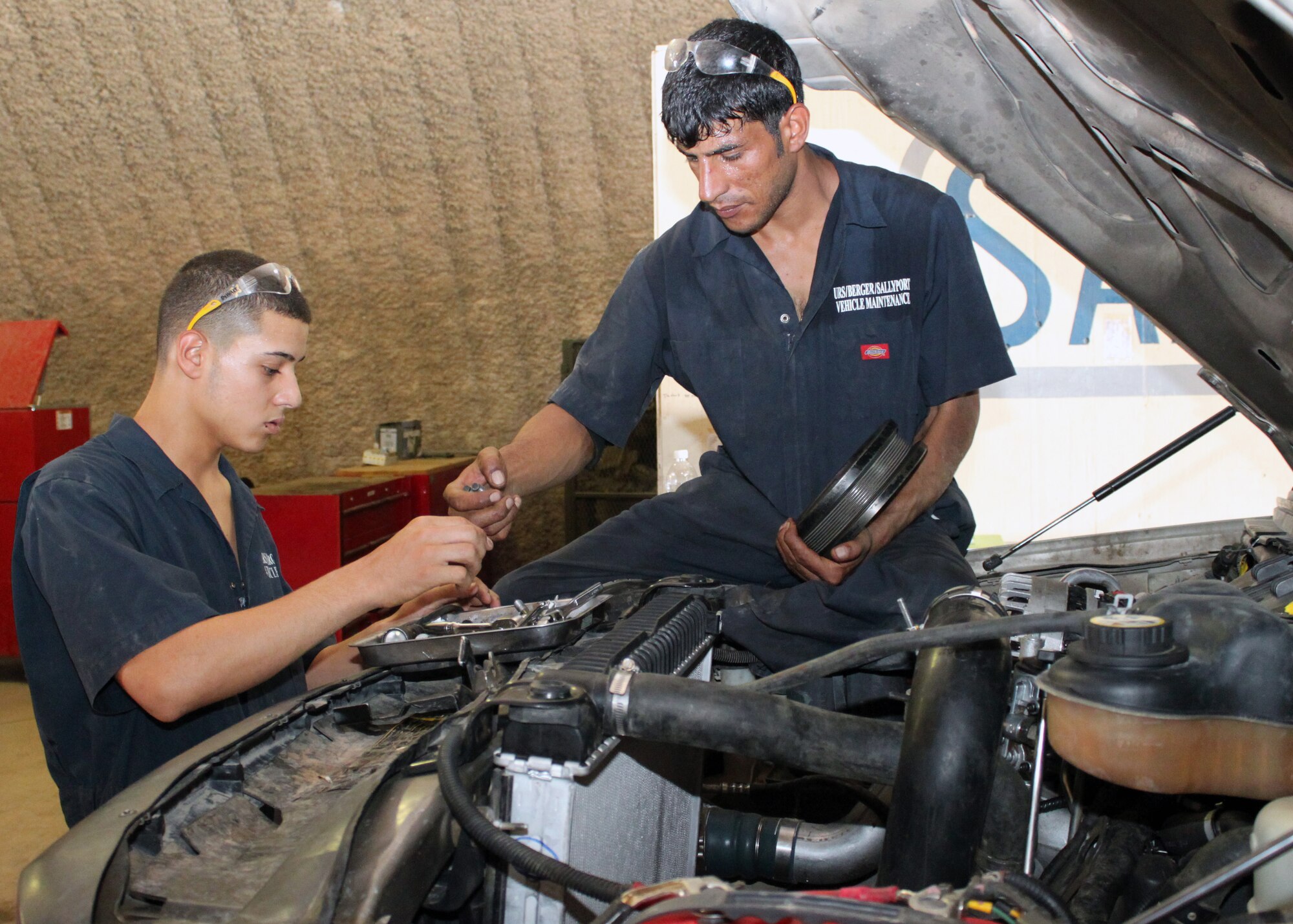 Mohammed Abbas (left) and Ehab Jahwad change fan belt parts from a truck engine Aug. 11, 2010, Joint Base Balad, Iraq. Engine familiarization is a crucial skill to becoming a master mechanic in the 332nd Expeditionary Logistics Readiness Squadron Vehicle Maintenance Flight Iraqi Mentorship Program. Mr. Abbas is an apprentice, while Mr. Jahwad is a master mechanic who recently graduated with seven other Iraqi vehicle maintainers during a ceremony Oct. 7, 2010. (U.S. Air Force photo/Tech. Sgt. Stacy Fowler)