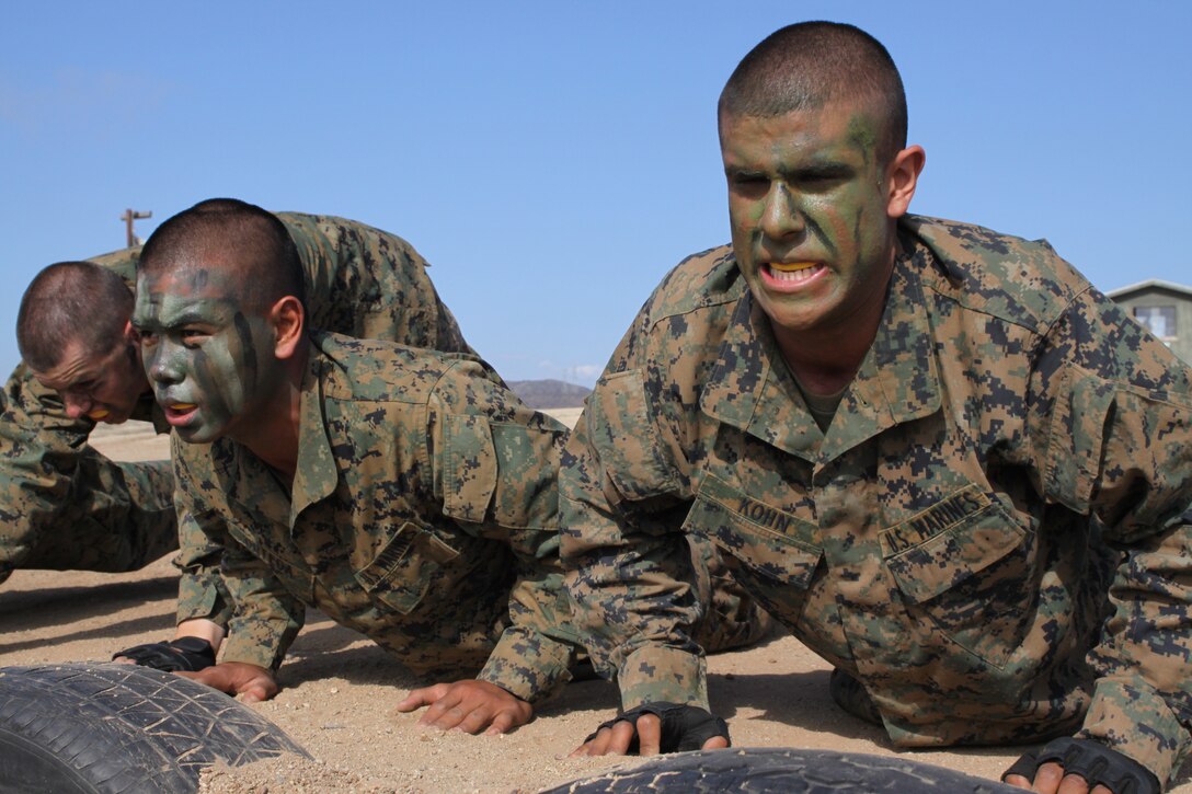 Recruits Enrique Ortega, left, and Justin Kohn, do push-ups while waiting for their turn to fight in the body sparring event at the Crucible Oct. 12. The recruits are from platoon 3208, Company I, 3rd Recruit Training Battalion, Recruit Training Regiment.