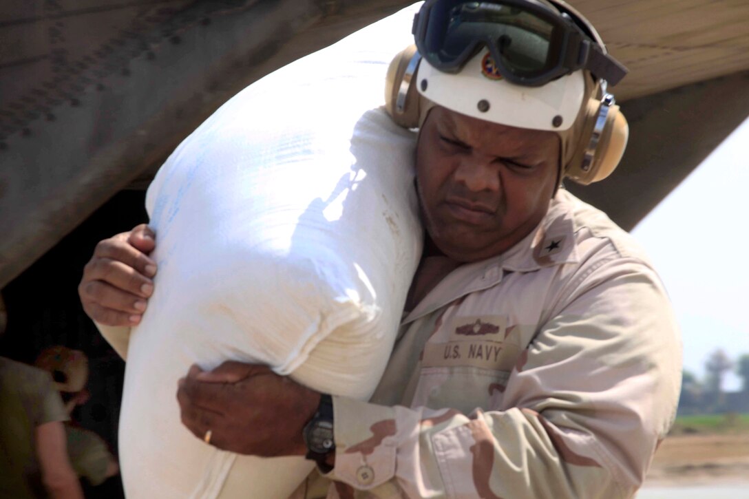U.S. Navy Rear Adm. Sinclair Harris, assists U.S. Marines unloading food from a CH-53E Super Stallion helicopter at a flood affected area during flood relief operations in the Pano Aqil province, Pakistan, October 10, 2010. Harris is the commanding officer of the Expeditionary Strike Group 5, and the Marines are assigned to Marine Medium Tilt Rotor Squadron 266 Reinforced.