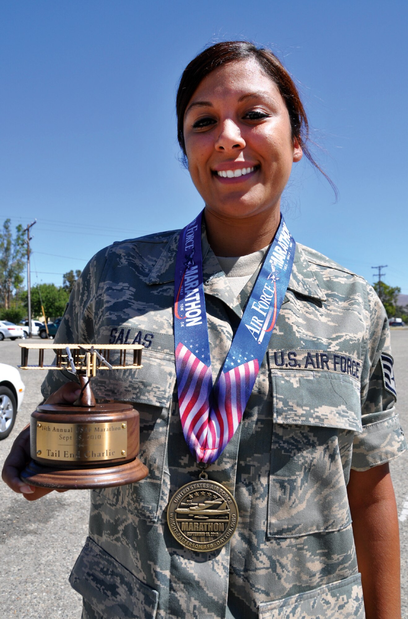 The day after her completion of the Air Force Marathon, Staff Sgt. Alicia Salas poses with her marathon finisher’s medal and the “Tail End Charlie” trophy for being the last person to cross the finish line. Sergeant Salas, an information technician with the 752nd Medical Squadron, finished the 26.2 miles in seven hours and 30 minutes. (U.S. Air Force photo by SrA Patrick Cabellon)