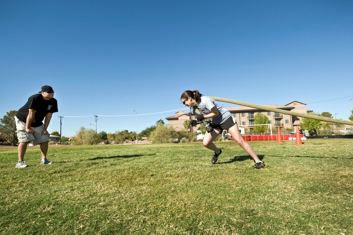 NELLIS AIR FORCE BASE, Nev.--  Staff Sgt. John Reinoehl, 99 Civil Engineer Squadron, Fire Protection encourages Capt. Sara Carrasco, U.S. Air Warfare Center Judge Advocate Office, to dig harder as she pulls a fire hose to the finish line during the 4th annual Fire Muster competition at the Nellis Sport Pavilion Oct. 8. (U.S. Air Force photo by Lawrence Crespo) 
 