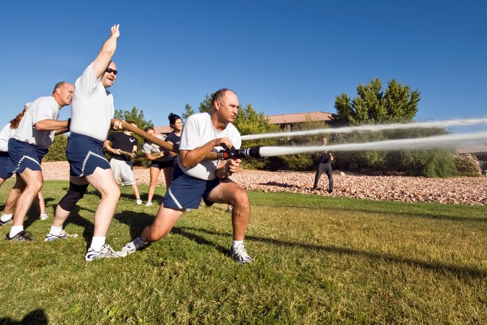 NELLIS AIR FORCE BASE, Nev.-- Chief Master Sgt. Timothy Jordon aims his fire hose  during the hose relay event as fellow Chief's encourage him to hit the target. Fourteen Nellis and Creech teams participated in this years Fire Muster competition at the Nellis Sport Pavilion Oct. 8.  (U.S. Air Force photo by Lawrence Crespo) 
 