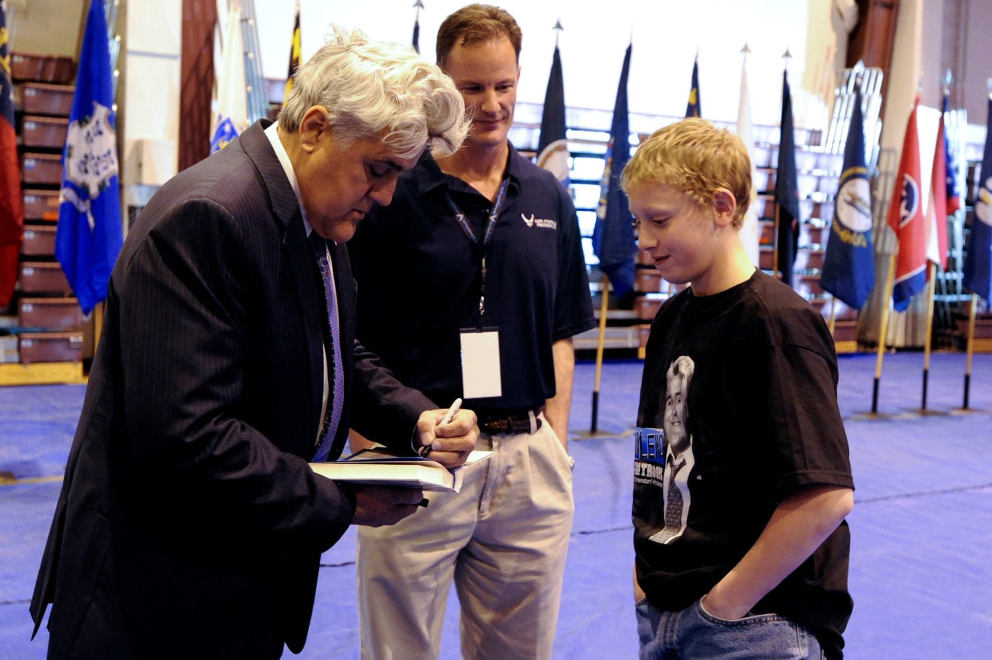 Jay Leno, signs a copy of his autobiography for Jared Layton, son of Senior Master Sgt. Timothy Layton, 962nd Aircraft Maintenance Unit, while 477th Fighter Group Commander Col. Eric Overturf looks on. The 477th FG is the Air Force Reserve associate unit for 3rd Wing. (U.S. Air Force photo\Staff Sgt. Joshua Garcia)