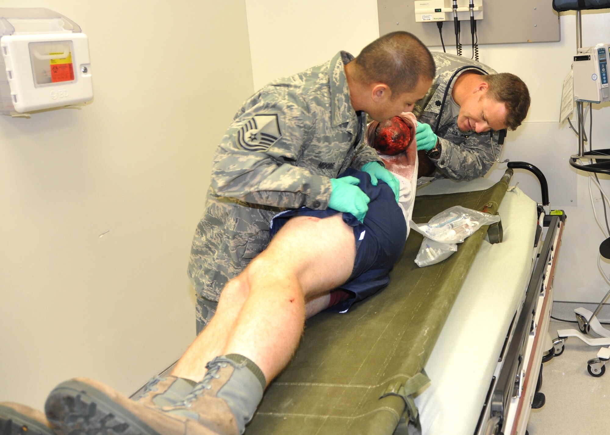 Master Sgt. Clint Moore, left, and Lt. Col. (Dr.) Joseph Pocreva, 81st Medical Operations Squadron, examine a injured patient in the emergency department to ensure he has no additional wounds.  (U.S. Air Force photo by Steve Pivnick)