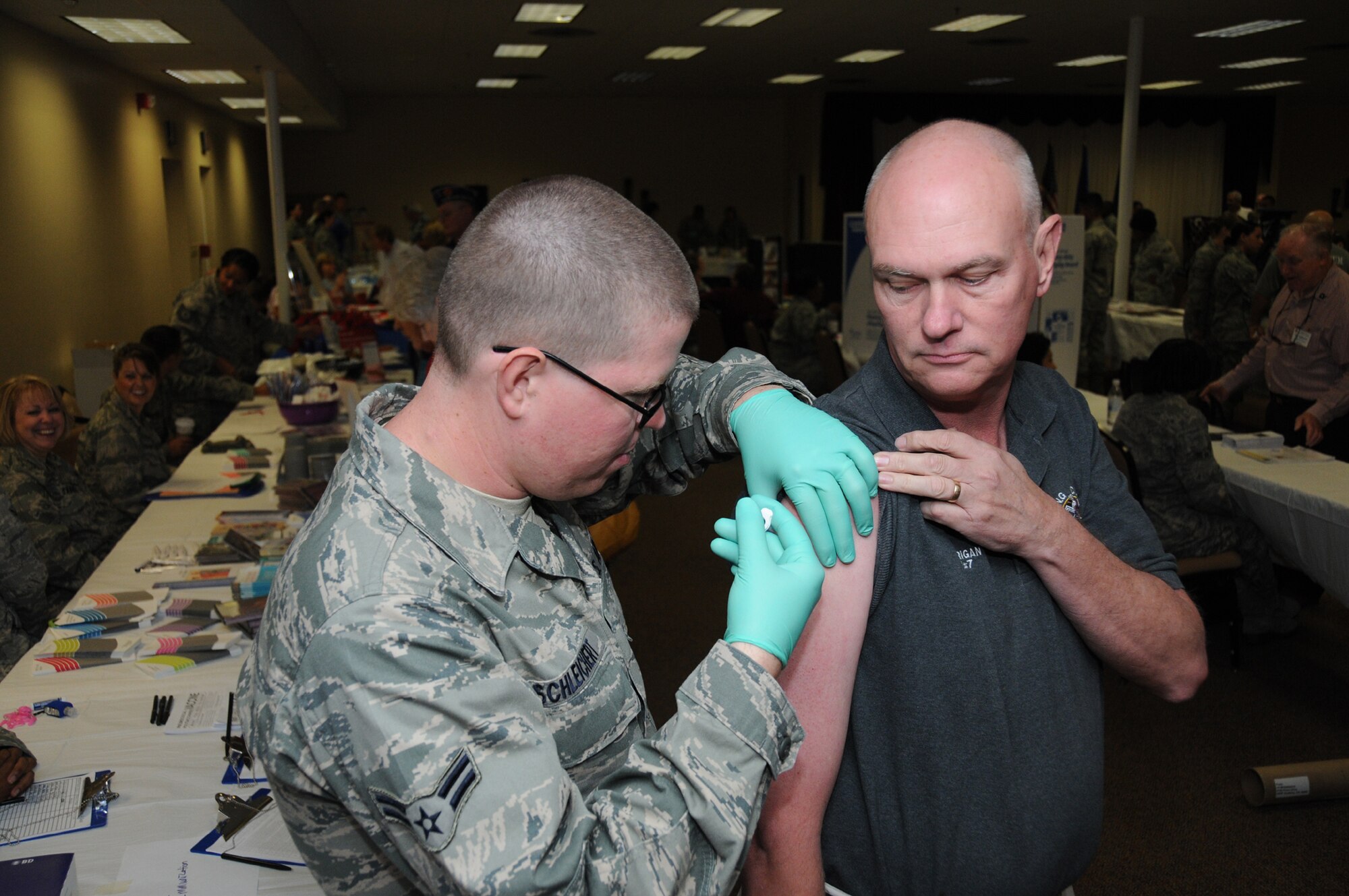 Airman 1st Class Brandon Schleichert, 81st MedicalOperations Squadron, gives a flu shot to retired chief Charlie Carrigan of Gulfport at Retiree Appreciation Day, Friday.  (U.S. Air Force photo by Kemberly Groue)