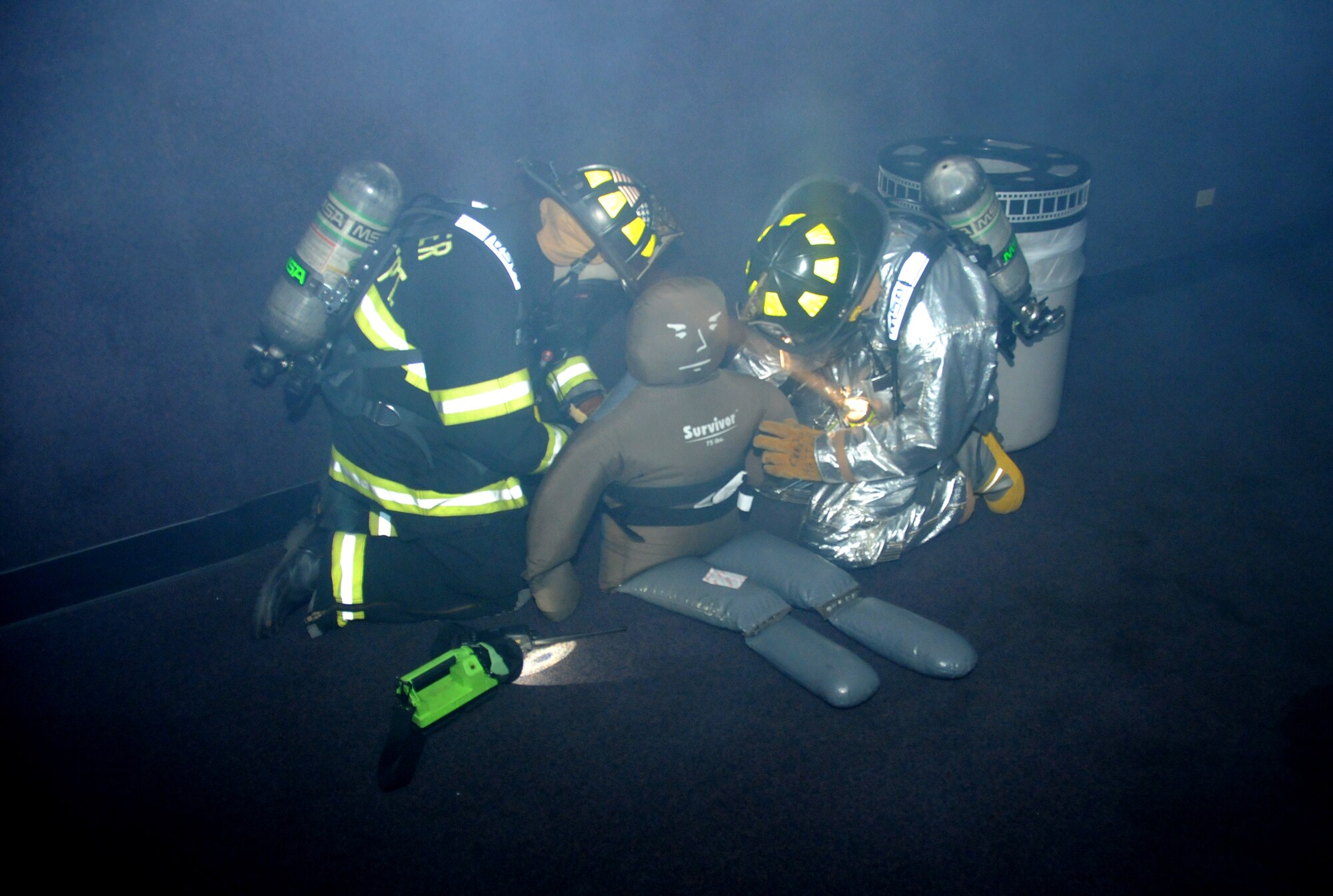 Donovan Oosterhuis, left, and Guy Chadwick secure straps around a “victim” to carry him to safety during an Oct. 6 fire exercise at Welch Auditorium. In the scenario, workers cleaning the building noticed heavy smoke and evacuated, but this one worker was missing.   (U.S. Air Force photo by Kemberly Groue)
