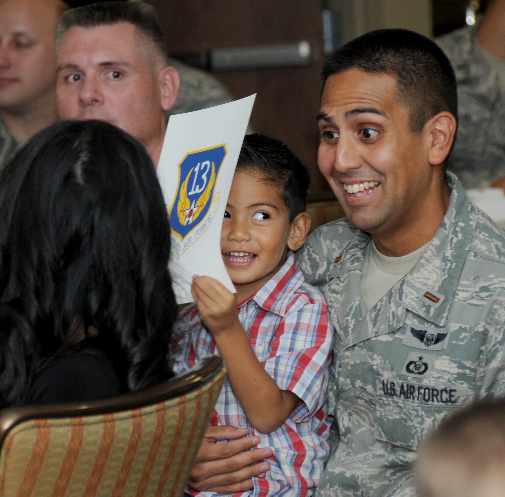 Second Lt. Carlos Rodriguez reacts with his wife Marife, left, and son Josiah, 2, after learning his assignment during ‘Drop Night’ Oct. 8. He’ll join the 56th Air Communications Squadron, Hickam Air Force Base, Hawaii.   (U.S. Air Force photo by Kemberly Groue)