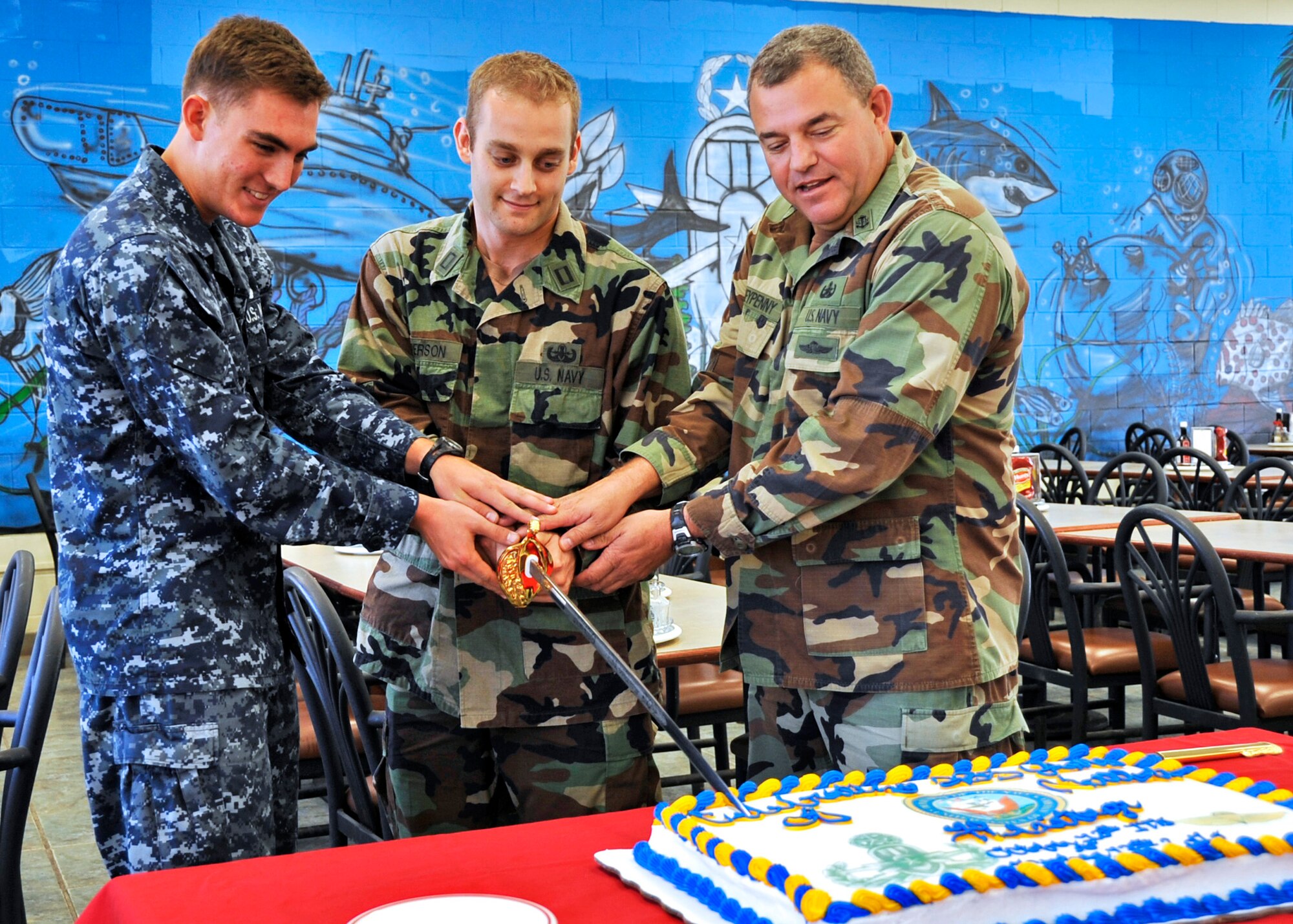 Students and instructors at the Navy Explosive Ordnance Disposal School celebrated the 235 birthday of the U.S. Navy Oct. 13, with the ceremonial cake cutting by the youngest and oldest Sailors.  (Left to right) Seaman Kyle Hall, 19-year-old student, Lt. Brian Anderson, instructor, and Chief Petty Officer Scott Moneypenny, 50-year-old instructor.  (U.S. Air Force photo/Samuel King Jr.)