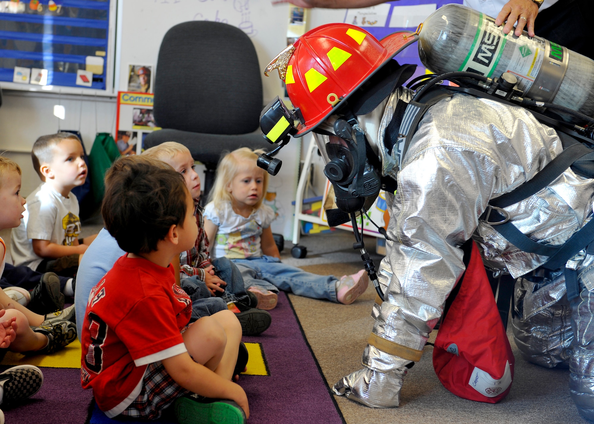 HOLLOMAN AIR FORCE BASE, N.M. -- Airman 1st Class Tristan Cooper, 49th Civil Engineer Squadron, crawls in his bunker gear to show children at Holloman Elementary how firefighters enter a burning building when responding to a fire emergency Oct. 8, 2010. During Fire Prevention Week, chief directors from the 49th CES Fire Department visited kindergarten classes to talk about what they should do in the case of a house fire. (U.S. Air Force photo by Senior Airman Veronica Stamps / Released)