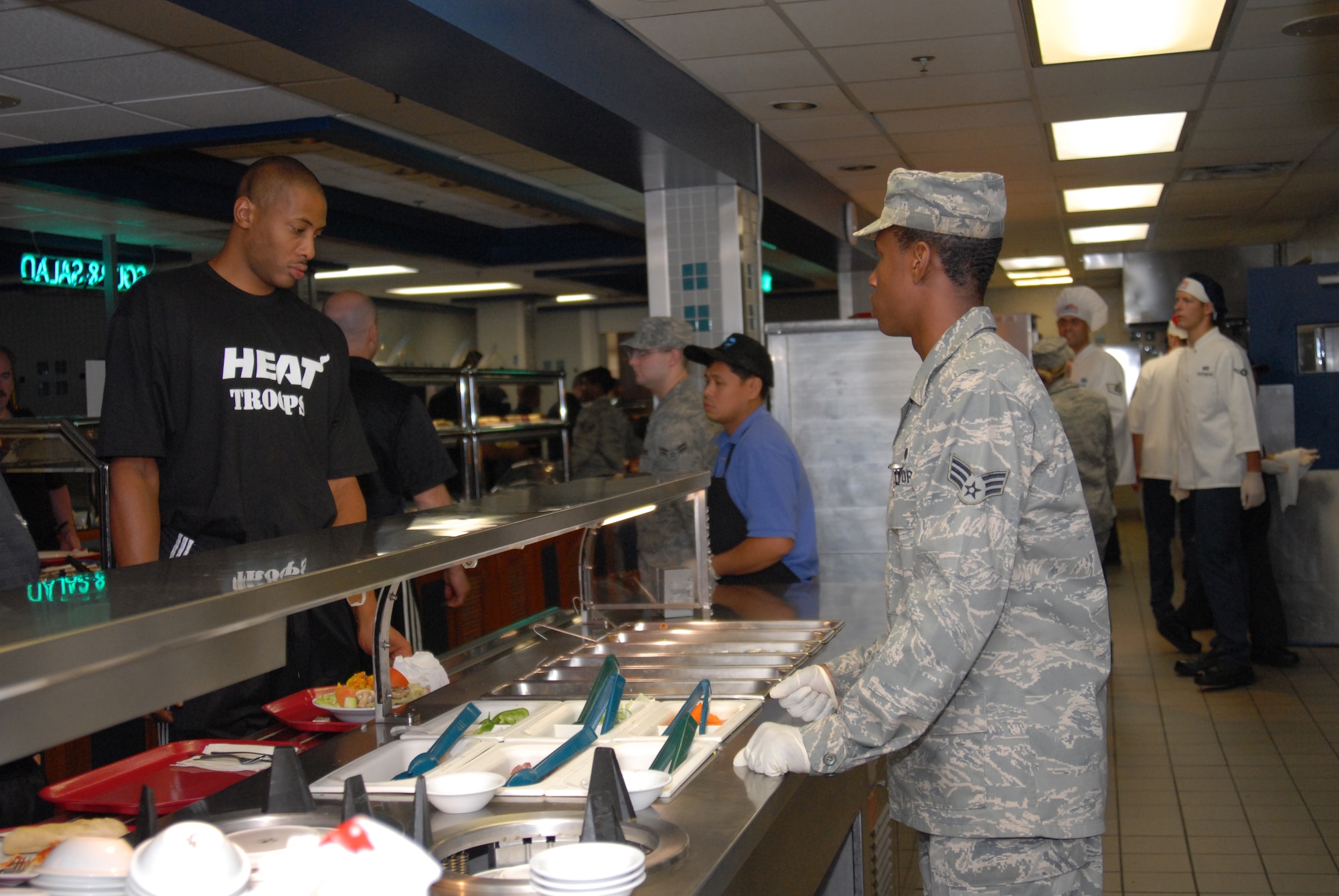 U. S. Air Force Senior Airman Javan King, 1st Special Operations Force Support Squadron food service specialist, gets a stir-fry order from Jamal Magloire, a Miami HEAT center, during a surprise lunch visit with Airmen at the Reef Dining Facility, Hurlburt Field, Fla., Sept. 30, 2010. The HEAT players and staff took time from their 2010 Training Camp to meet with Airmen and learn the missions of Hurlburt Field and Eglin Air Force Base.  (DoD photo by U. S. Air Force Staff Sgt. Orly N. Tyrell/Released)
