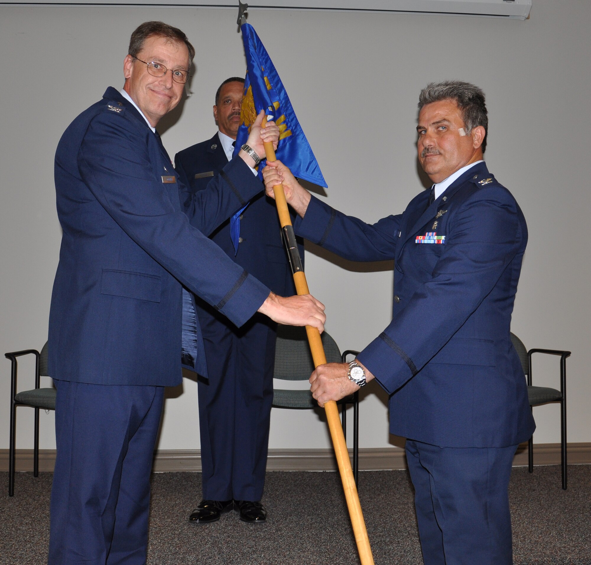 WRIGHT-PATTERSON AIR FORCE BASE, Ohio – Col. Stephen Goeman, 445th Airlift Wing commander, passes the guidon to Col. Akram Sadake, on the right, during a change of command ceremony Sept. 11. (U.S. Air Force photo/Senior Airman Mikhail Berlin)