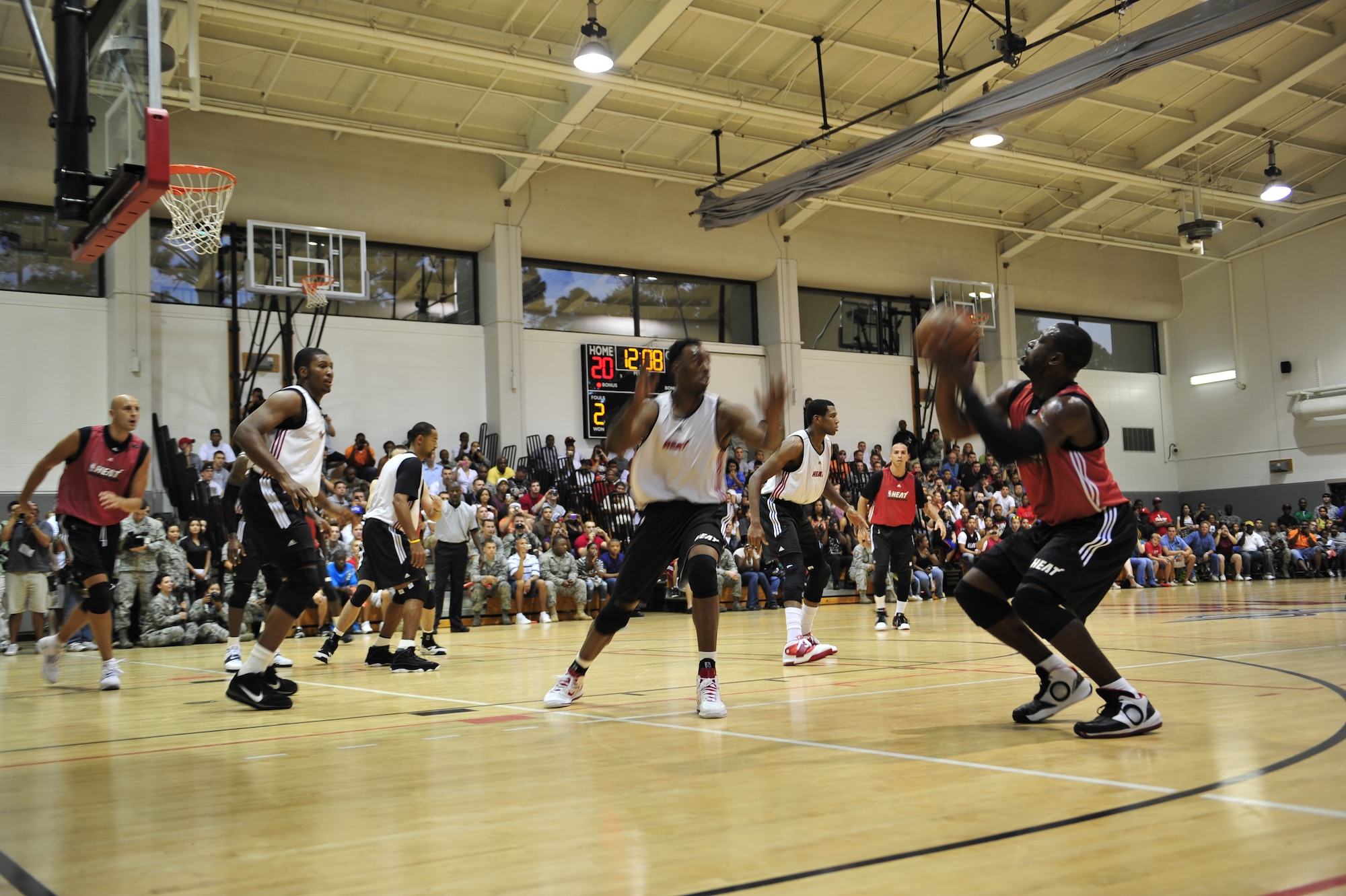 Dwyane Wade, a Miami HEAT player, sets up for a jump shot as a player runs in to block during a scrimmage at the Aderholt Fitness Center, Hurlburt Field, Fla., Oct. 1, 2010. The HEAT took time out from their training camp to display their skills in front of more than 500 Hurlburt and Eglin Air Force Base Airmen, DoD Civilians and dependents. (DoD Photo by Staff Sgt. Stephanie Jacobs/RELEASED)