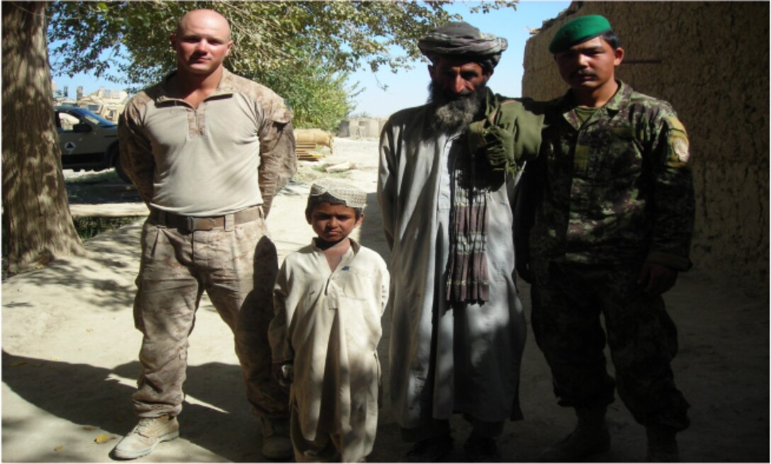 Corporal Richard J. Zondor, a rifleman with Combined Anti-armor Team 2, 3rd Battalion, 1st Marine Regiment, poses with the six-year-old Fada Mohamad; his father, Haji Mirbash; and Afghan National Army soldier Narhaden, Oct. 14, in Laki, Helamand province, Afghanistan.  While holding security at a nearby checkpoint, Zondor dove into a canal to save Mohamad, who had fallen in while hearding sheep across a bridge with his father.
