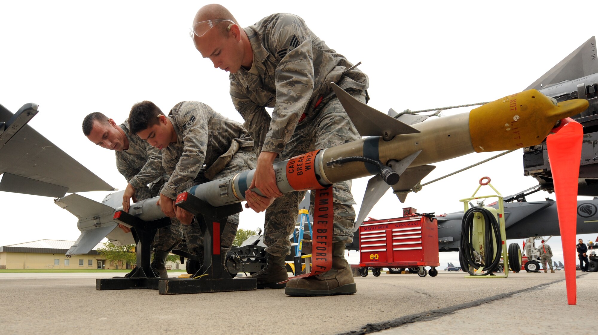 MOUNTAIN HOME AIR FORCE BASE, Idaho – Staff Sgt. Kevin Sitko (left), Airman 1st Class Jeffrey Brockman (middle) and Senior Airman Derek Pennington (right), all 389th Fighter Squadron weapons load crew members, prepare an AIM-120 missile before a weapons load crew competition outside of hangar 1331 Oct. 8. The load crews go through a series of three categories for the competition: an equipment inspection, a written test and a timed loading section. The 428th Fighter Squadron took first place this quarter. (U.S. Air Force photo by Senior Airman Debbie Lockhart)