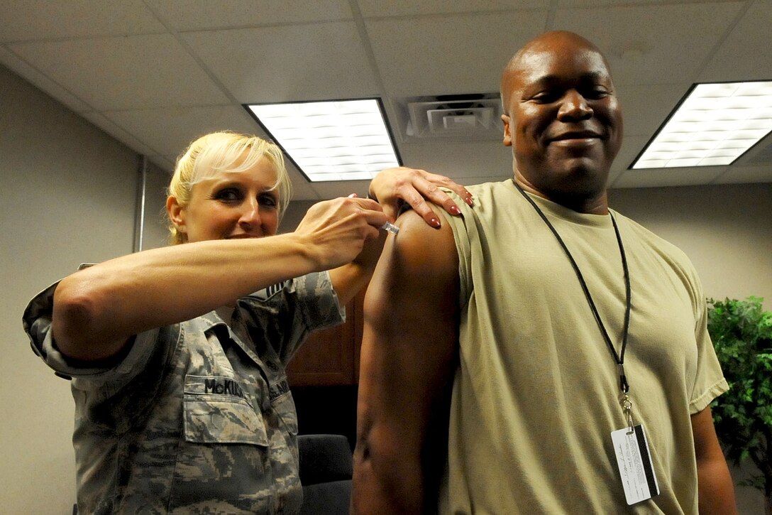 LANGLEY AIR FORCE BASE, Va -- U.S. Army Col. Reggie Austin, 633d Air Base Wing vice commander, receives a flu shot from Master Sgt. Bonnie McKusick, 633d ABW command chief assistant, Oct. 14. This season’s vaccines protect not only against H1N1 but also against two other influenza viruses: H3N2 virus and an Influenza B virus. (U.S. Air Force photo/Staff Sgt. Ashley Hawkins)