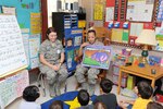 Airmen Tracy Moore and Marissa Pickraum, both with the 319th Training Squadron, read a story to children at Valley Hi Elementary Oct. 7. The Airmen were among 65 Joint Base San Antonio members, including servicemembers and civilians, who participated in the quarterly program to read to children in schools surrounding JBSA installations. (U.S. Air Force photo/Alan Boedeker)
