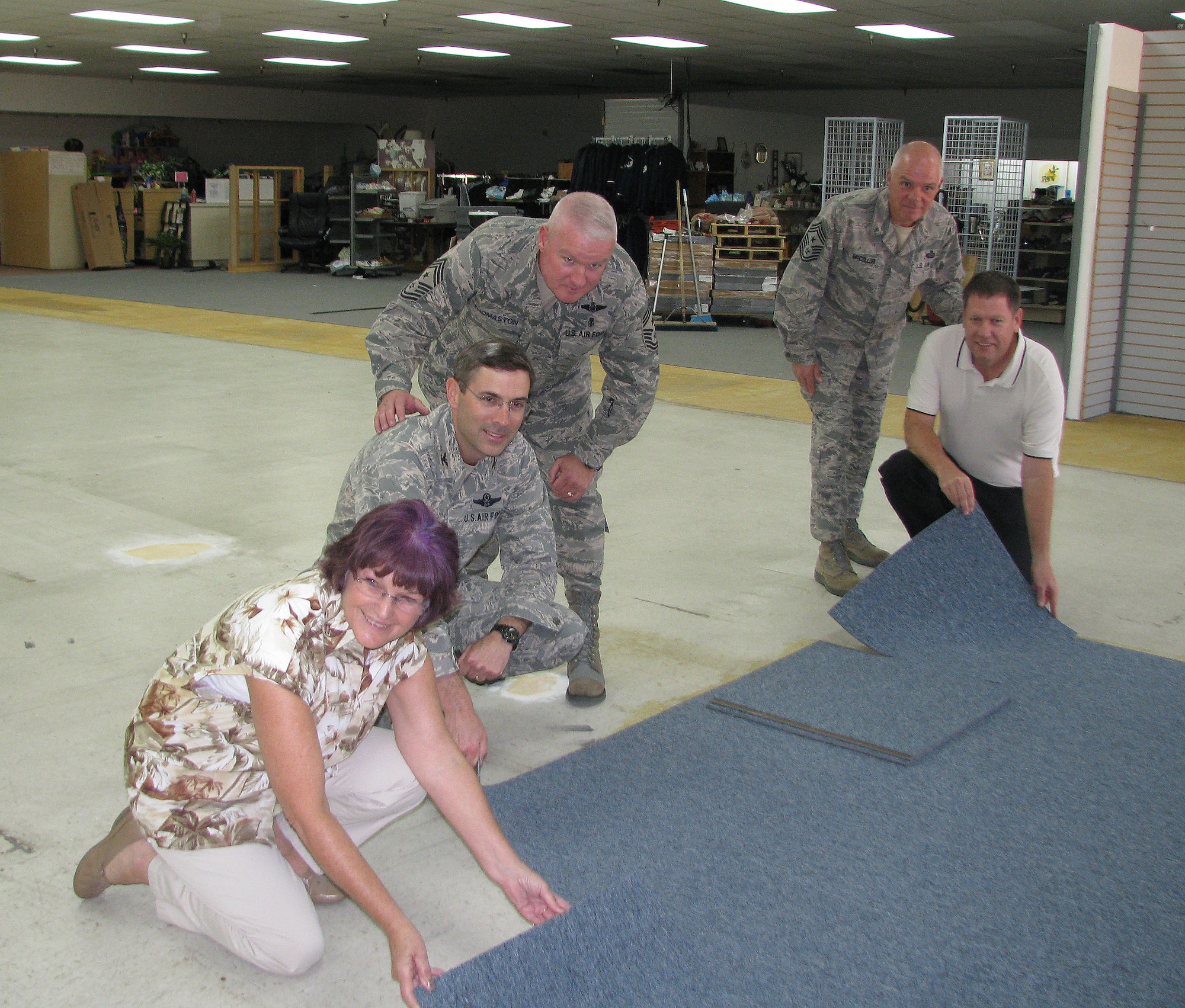 Edwards leadership and Civ-Mil members join forces to install new carpet tiles on the floor of the Airman's Attic. From left: Michele Slade, Col. Gregory J. Schwab, 95th Air Base Wing commander, Chief Master Sgt. Bill Thomaston, 95th Air Base Wing command chief, Chief Master Sgt.Chris McCollor,412th Test Wing command chief and Danny Bazzell, director of Strategic Communications for the Edwards Civ-Mil group. (Air Force photo by Diane Betzler)