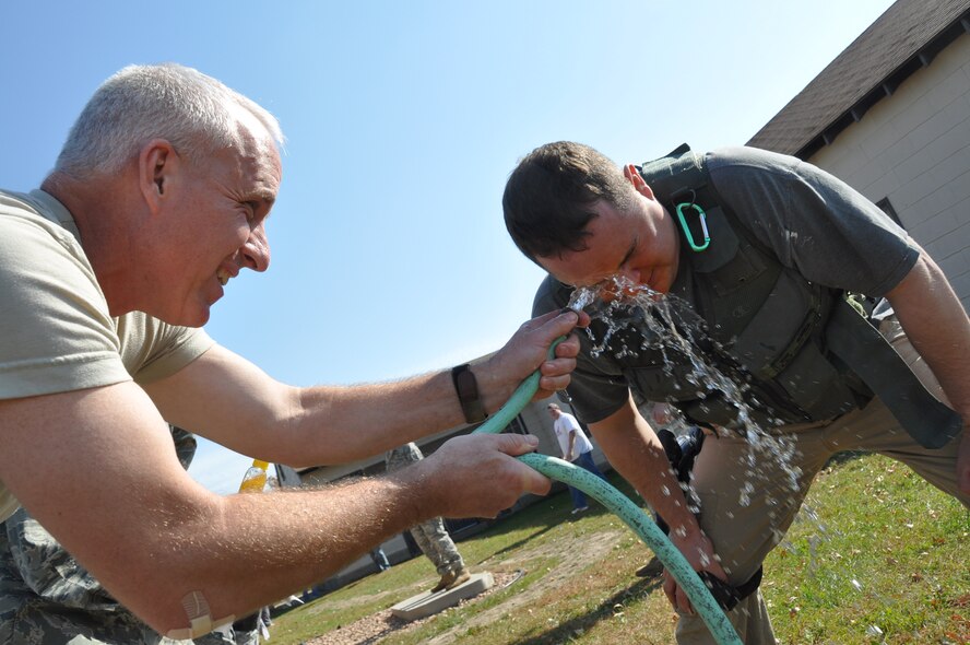 Tech. Sgt. Jesse Vaneusse, 934th Security Forces Squadron, gets a welcome splash of cold water after performing a series of tasks with pepper spray in his face during training Oct. 12.  The training enabled SFS members to experience and understand the effects of pepper spray and practice performing their duties after being sprayed. (Air Force Photo/Paul Zadach) 