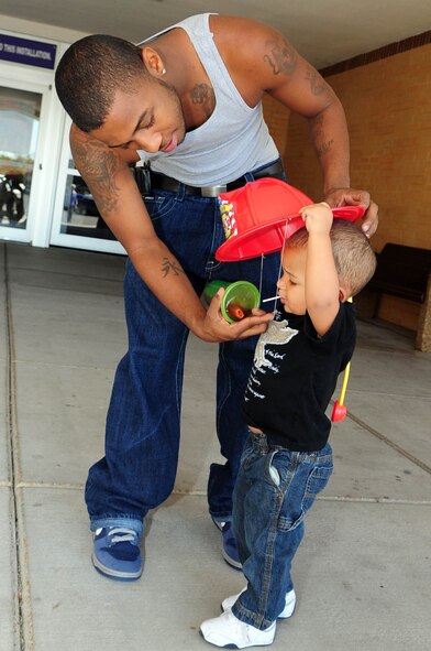 BARKSDALE AIR FORCE BASE, La. -- Justin Smith helps his son, Justin, 2, put on a toy firefighter's hat outside the Barksdale Base Exchange Oct. 7. Members of the Barksdale Fire Department greeted Airmen at the BX to hand out goodies and to encourage them to check their smoke detectors and fire extinguishers as part of Fire Prevention Week. (U.S. Air Force photo by Senior Airman Joanna M. Kresge) 