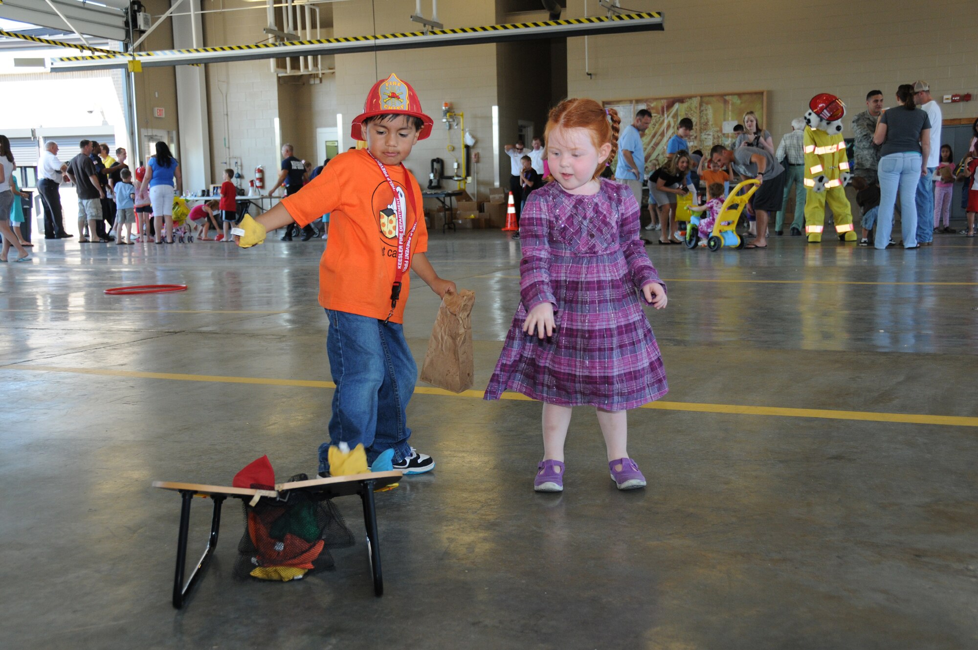 Carlos Hurtado Jr., 4, and Haylee Murphy, 3, play the bean bag toss game at the fire department's open house, Oct. 9.  Carlos is the son of Tech. Sgt. Carlos and Veronica Hurtado, 81st Training Support Squadron.  His dad is currently deployed to Honduras.  Haylee's parents are Staff Sgt. Kyle and Jessica Murphy.  Sergeant Murphy is a Keesler firefighter.  (U.S. Air Force photo by Kemberly Groue)