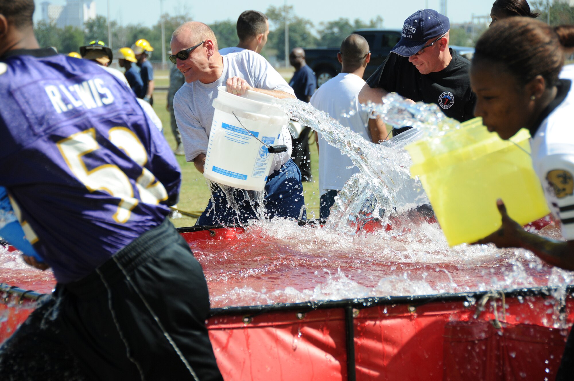 From left, Airman Kenneth Wise, 81st Mission Support Group; Brig. Gen. Andrew Mueller, commander, and Col. Glen Downing, vice commander, 81st Training Wing; AND Airman 1st Class Ivana Richardson, 81st MSG) fill buckets for the bucket brigade competition at the fire muster, Oct. 8.  (U.S. Air Force photo by Kemberly Groue)