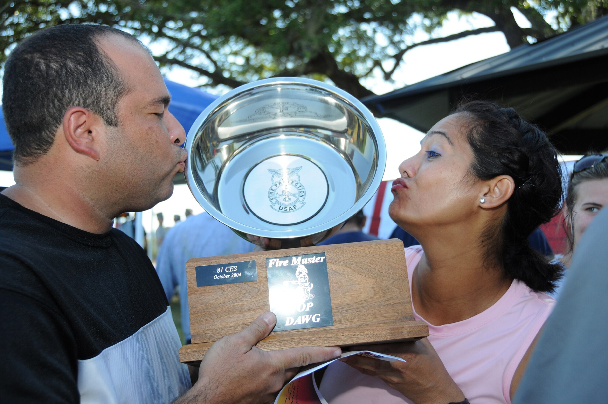 Tech. Sgts. Stephen Dereis and Caroline Bunce from the 81st Dental Squadron Flossinators, kiss the team’s first-place trophy at Friday’s firemuster.  (U.S. Air Force photo by Kemberly Groue)