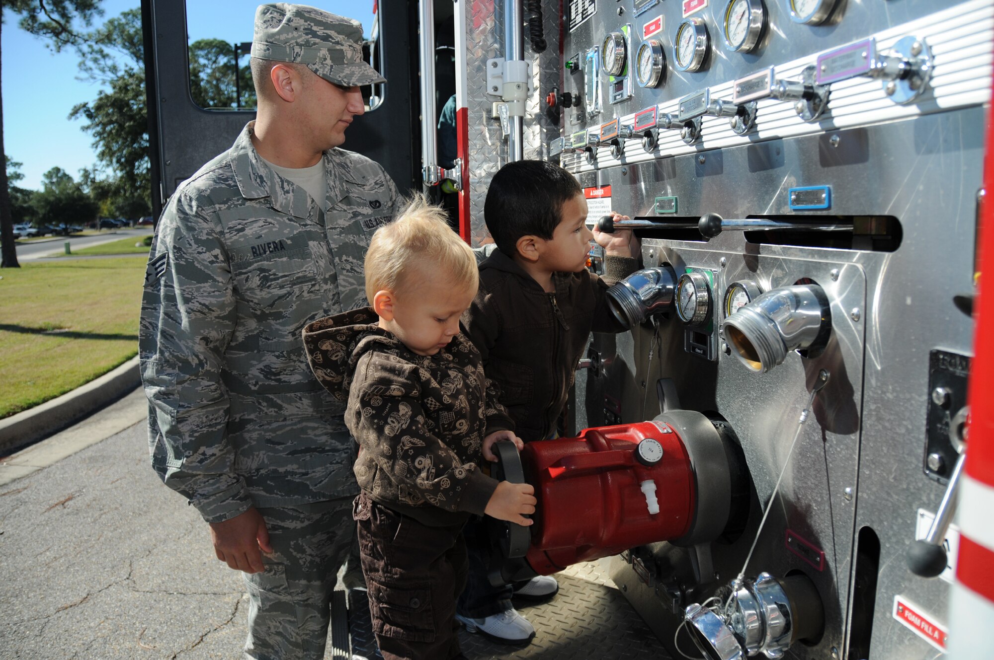 Senior Airman Roberto Rivera, a Keesler firefighter, shows 2-year-olds Gavin Butler and Angel Lujano the controls on the side of a fire truck during a visit to the child development center Oct. 5. Gavin’s parents are Amber Butler, 81st Force Support
Squadron, and Senior Airman Thomas Butler, 81st Comptroller Squadron. Angel’s parents are Senior Airman Mirna and Angel Lujano, 81st Logistics Readiness Squadron.  (U.S. Air Force photo by Kemberly Groue)