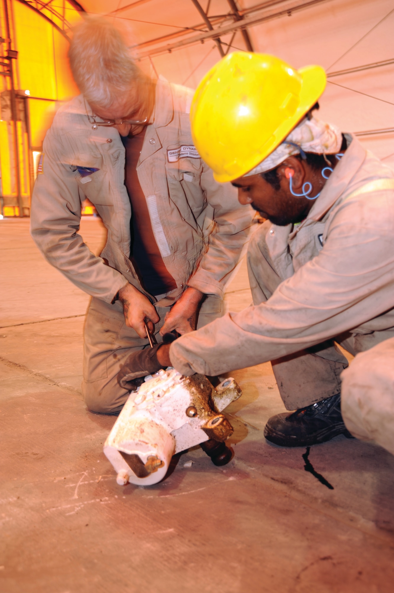 Kevin Woodward (left) and Murugan Moorphy, BDRF teardown crew, disassemble a steering gear removed from a battle damaged Stryker. The steering gear will be salvaged and reused on the Stryker after it is fully repaired.