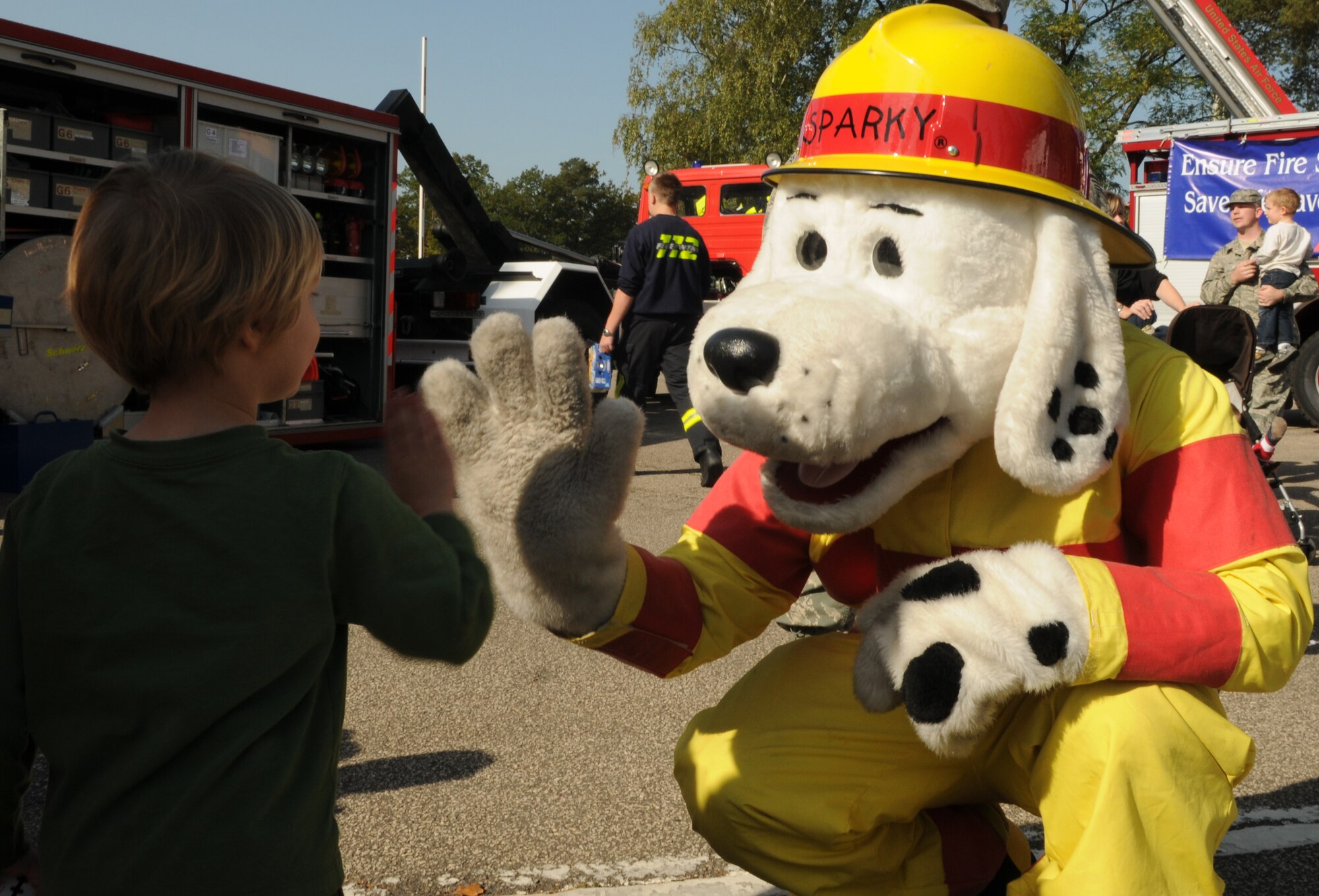 SPANGDAHLEM AIR BASE, Germany – Three-year-old Daniel Brown gives a high-five to Sparky the fire safety dog after a fire truck parade through base housing as part of Fire Prevention Week  Oct. 9.  The day also included a fire brigade parade of German and U.S. fire trucks through Spangdahlem’s housing loop and fire emergency services activities such as auto extrication demonstration, U.S. and German fire truck static displays, hose bowling, bunker drills, a smoke house, stove safety and a free barbeque. Since 1922, Fire Prevention Week has taken place in the U.S. to increase fire safety awareness. (U.S. Air Force photo/Senior Airman Nick Wilson)