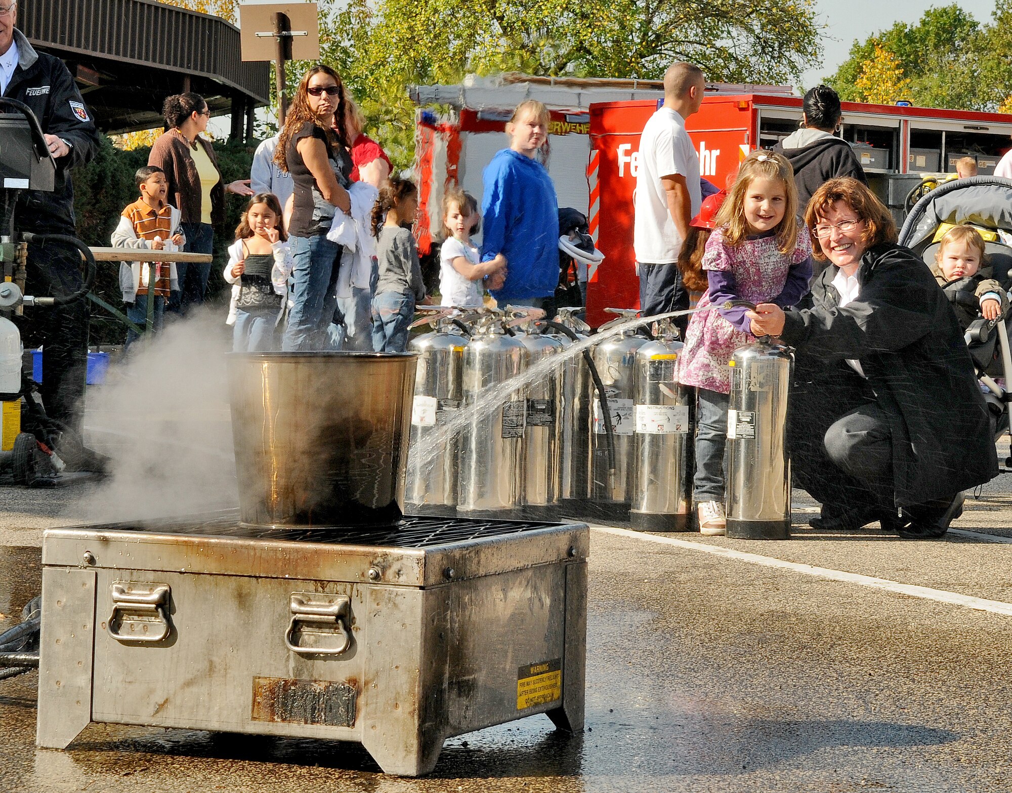 SPANGDAHLEM AIR BASE, Germany – Inge Lersch, 52nd Civil Engineer Squadron fire department assistant chief of local national affairs, helps four-year-old Leni Thies put out a fire during a fire extinguishing demonstration as part of Fire Prevention Week Oct. 9.  The day also included a fire brigade parade of German and U.S. fire trucks through Spangdahlem’s housing loop and fire emergency services activities such as an auto extrication demonstration, U.S. and German fire truck static displays, hose bowling, bunker drills, a smoke house, stove safety and a free barbecue. Since 1922, Fire Prevention Week has taken place in the U.S. to increase fire safety awareness. (U.S. Air Force photo/Senior Airman Nick Wilson)