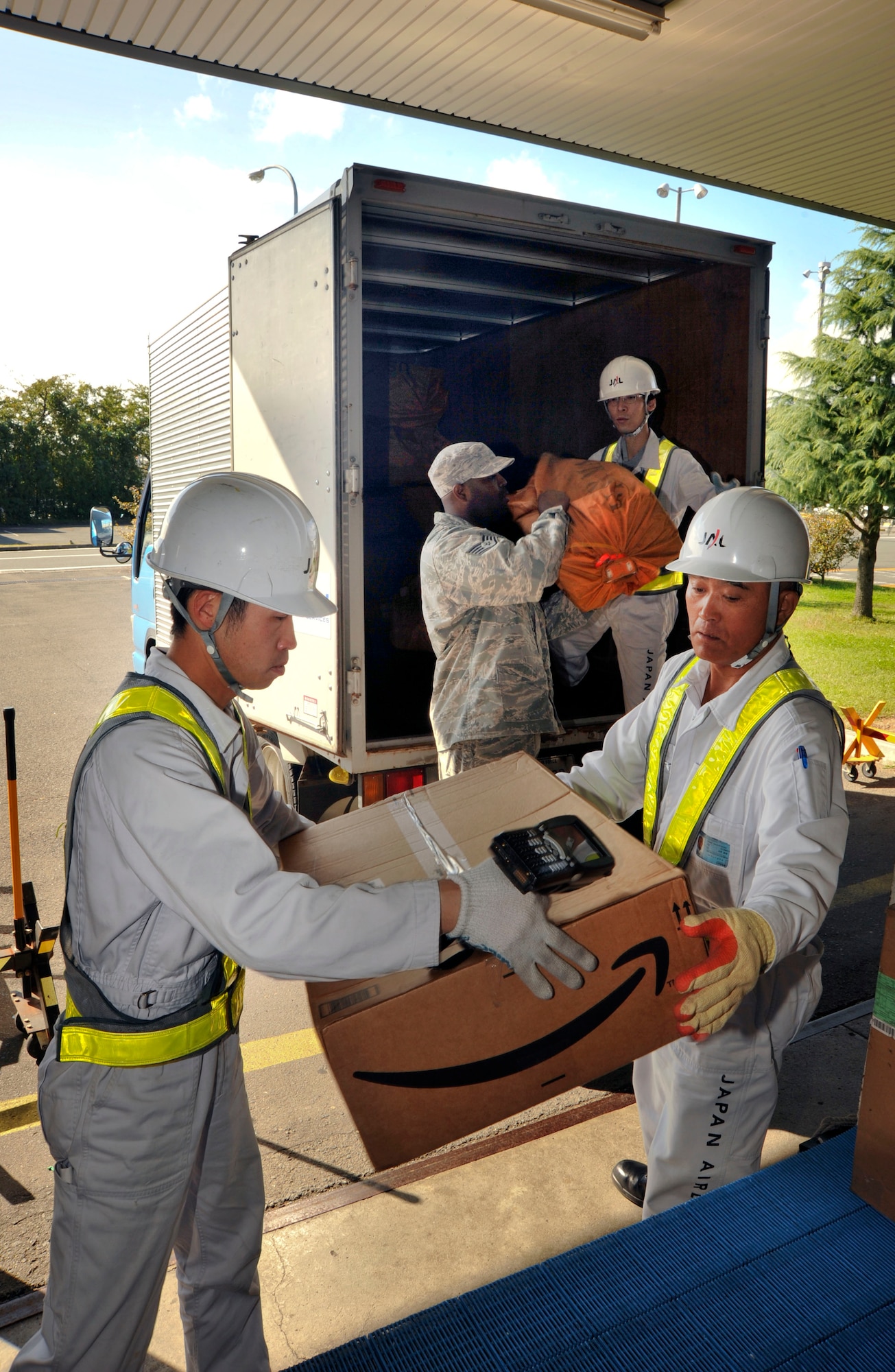 U.S. Air Force Staff Sgt. James Denson, center, 35th Communications Squadron and members of Japanese Airlines mail distribution center at the Misawa International Airport load mail into a truck Oct. 13, 2010. The mail is then taken to the base post office to be sorted and delivered to Misawa Air Base, Japan. The mail is usually picked up three times a day, depending on flight schedules. (U.S. Air Force photo by Tech. Sgt. Russell McBride/Released)