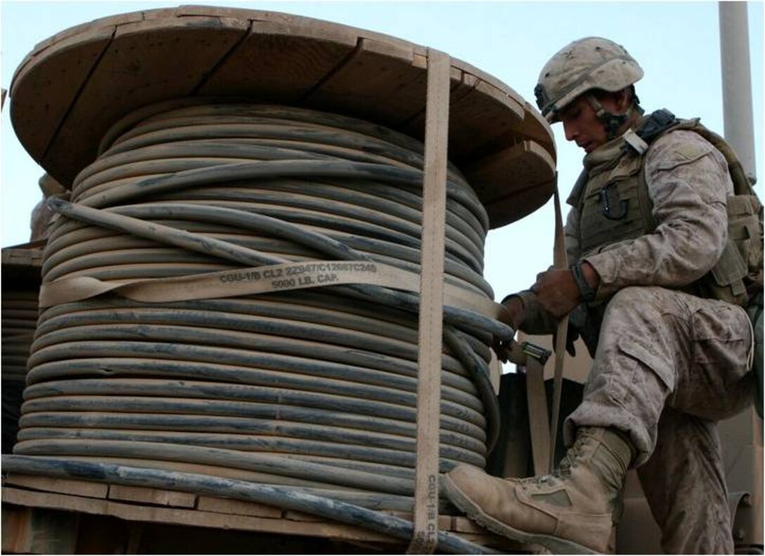 Lance Cpl. Horacio Vieyra, 20, a motor transport operator with 2nd platoon, Motor Transport Company A, Combat Logistics Battalion 3, 1st Marine Logistics Group (Forward), ties down a spool of wire with a ratchet strap during a resupply convoy, Oct. 14.