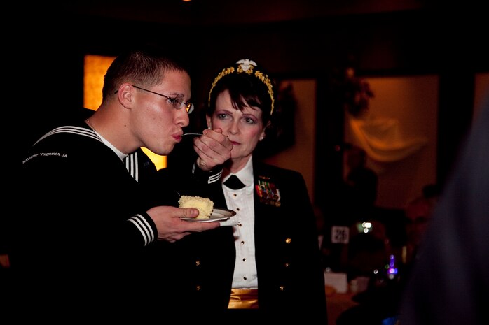 Seaman Zachary Hallowood, youngest sailor present, eats the first piece of cake, while Cmdr. Sheri Coleman, oldest active duty sailor present, watches during the Navy Birthday Ball here Oct. 15. By tradition, the oldest active duty Navy member present passes the first piece of cake to youngest to symbolize the passing of the proverbial torch to the future naval leadership.
