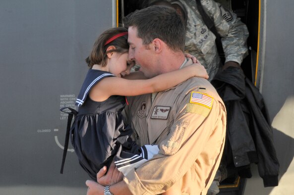 PATRICK AIR FORCE BASE, Fla. - 1st Lt. Patrick Woodruff, HC-130P/N King pilot, 920th Rescue Wing here, hugs his daughter Ella, 5, after returning from a deployment to Africa October 15, 2010. He piloted a wing aircraft with a crew of 5, all the way from Africa to Florida with 20 Airmen aboard. Upon landing, he was also greeted by his wife, Lauren, and black labrador retriever, Belle. The Air Force Reservists were deployed to the horn of Africa region were they provided combat search and rescue support. All together 63 Reservists were deployed for 45 days. The Wing is one of the most called upon units in the nation. Airmen deploy often supporting combat search and rescue worldwide. (U.S. Air Force Photo/Capt. Cathleen Snow)